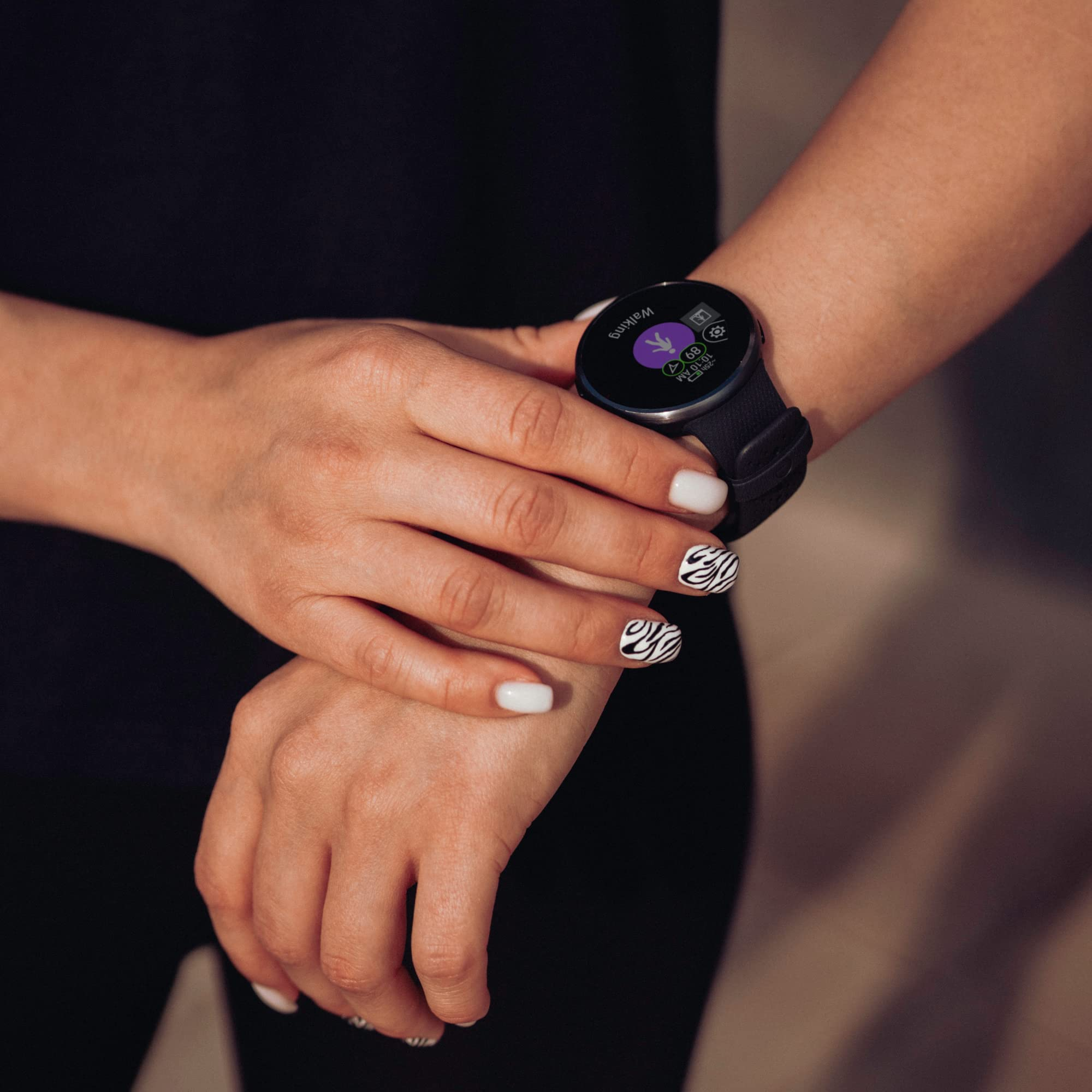 Person mit schwarzer Smartwatch und Gehanzeige, Hände zeigen Nägel im Zebramuster.