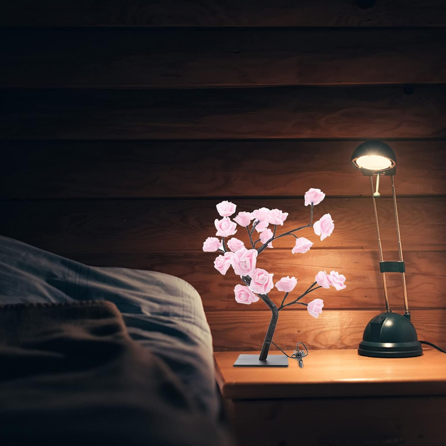 Eine leuchtende rosa Rosenbaumlampe und eine Schreibtischlampe stehen auf einem Nachttisch.