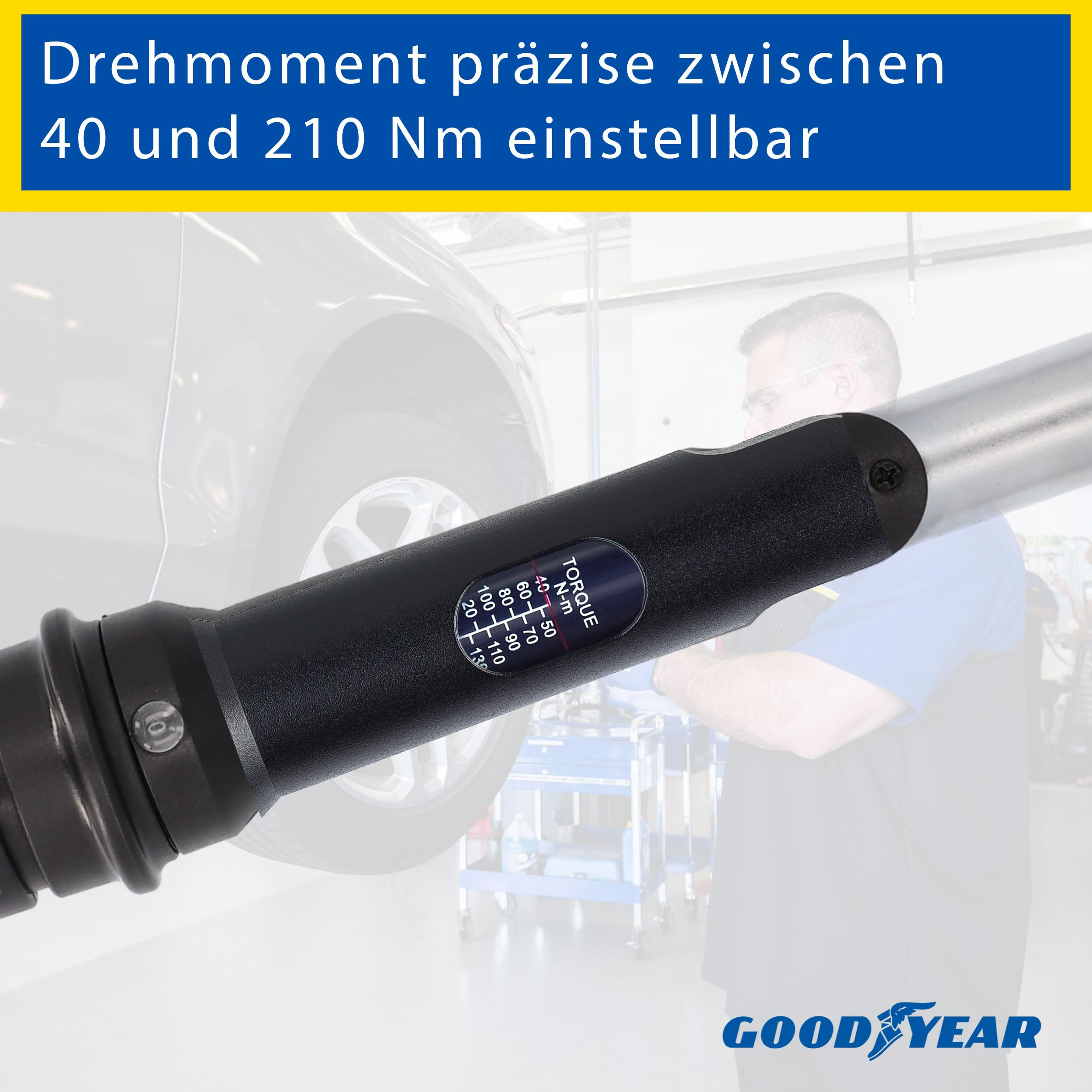 Ein Drehmomentschlüssel mit digitaler Anzeige, im Hintergrund ein Autoreifen und ein Mechaniker.