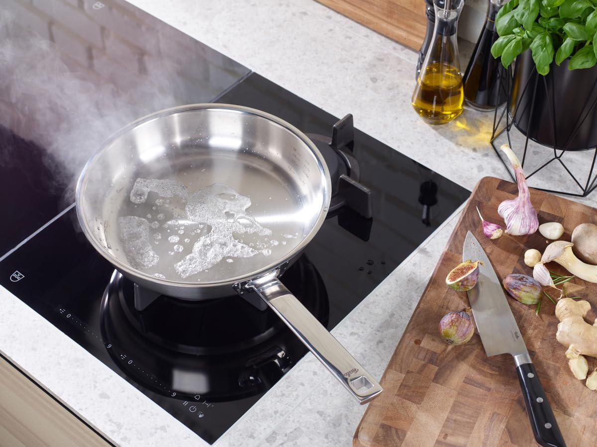 Une poêle en acier inoxydable avec du beurre fondu sur une cuisinière, à côté d'une planche à découper.