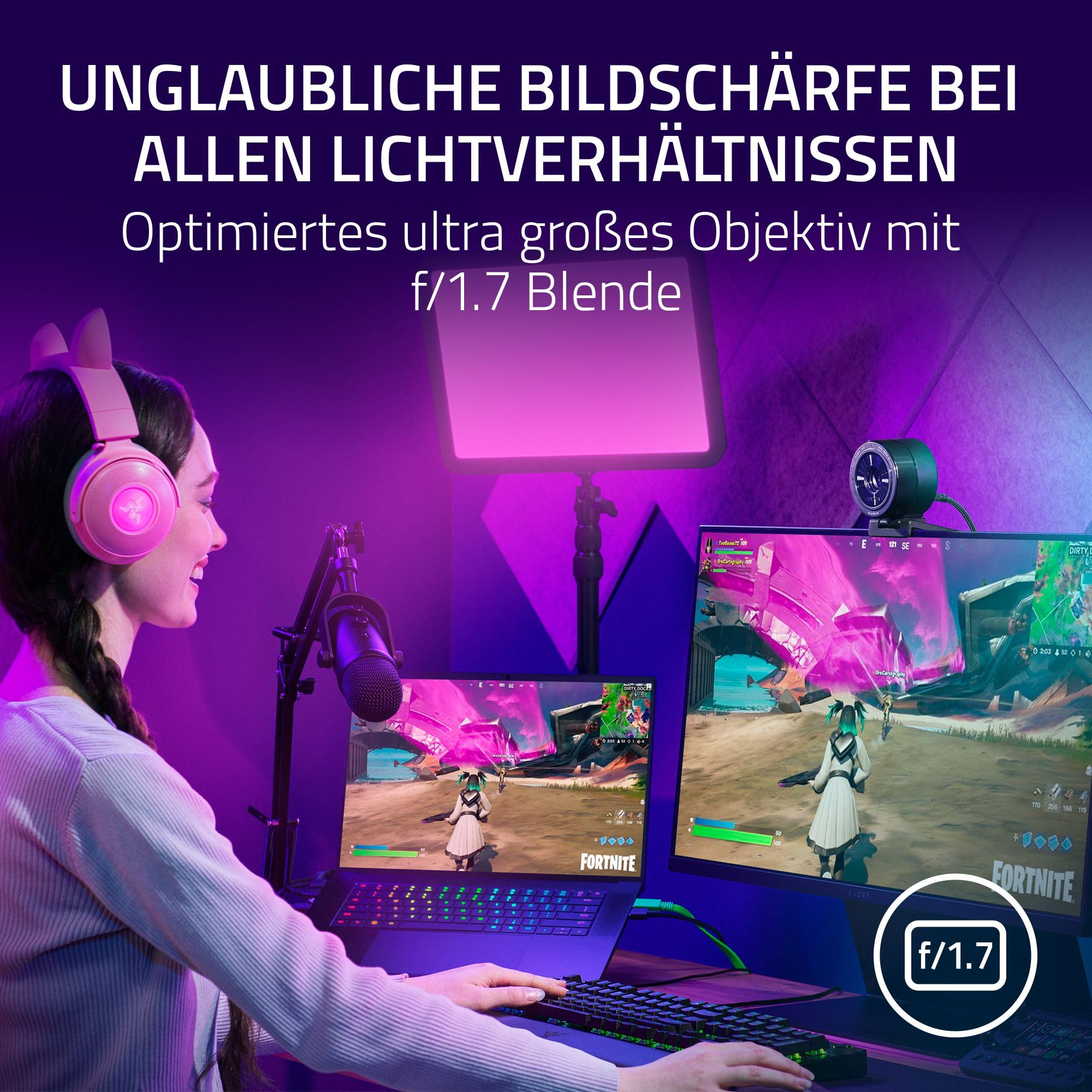 Streamer con cuffie rosa gioca a Fortnite su laptop e monitor con luce viola.