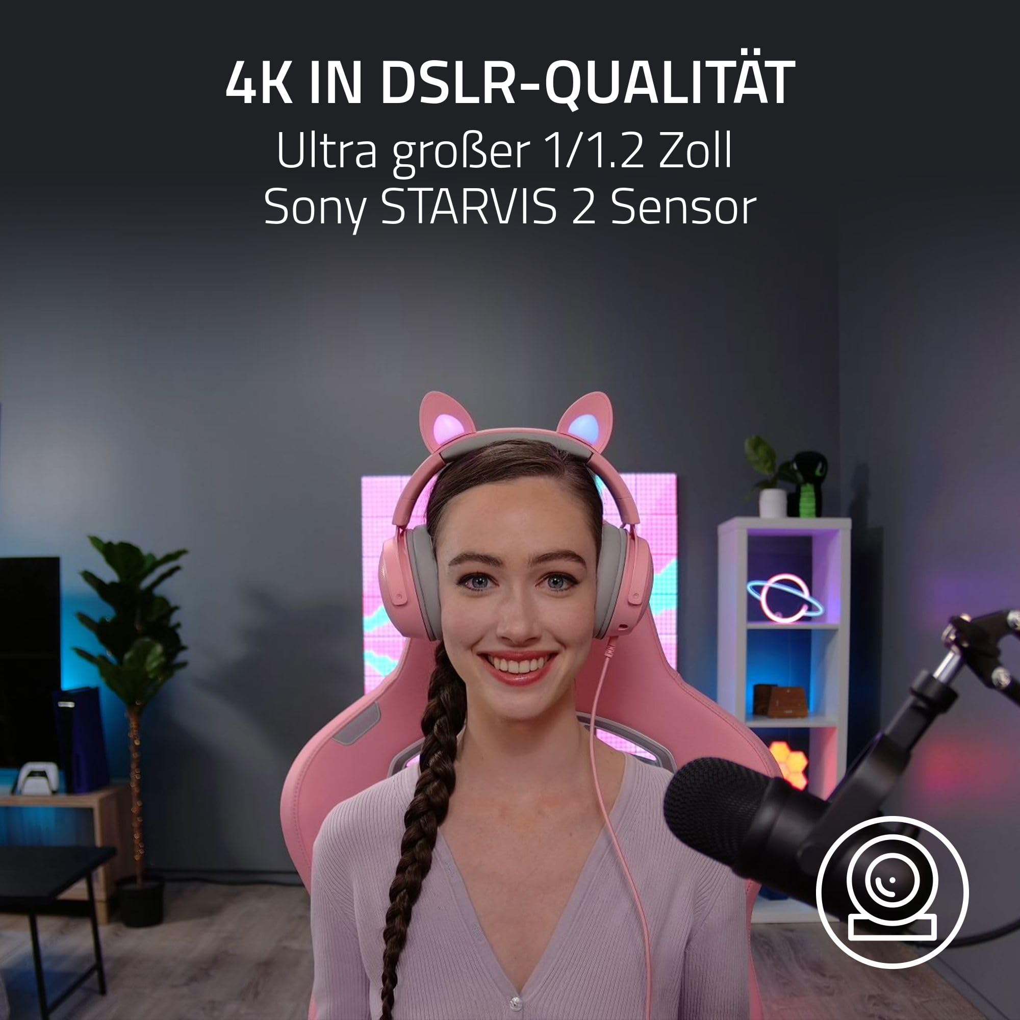Una donna sorridente con cuffie da gatto rosa siede su una sedia da gaming rosa.