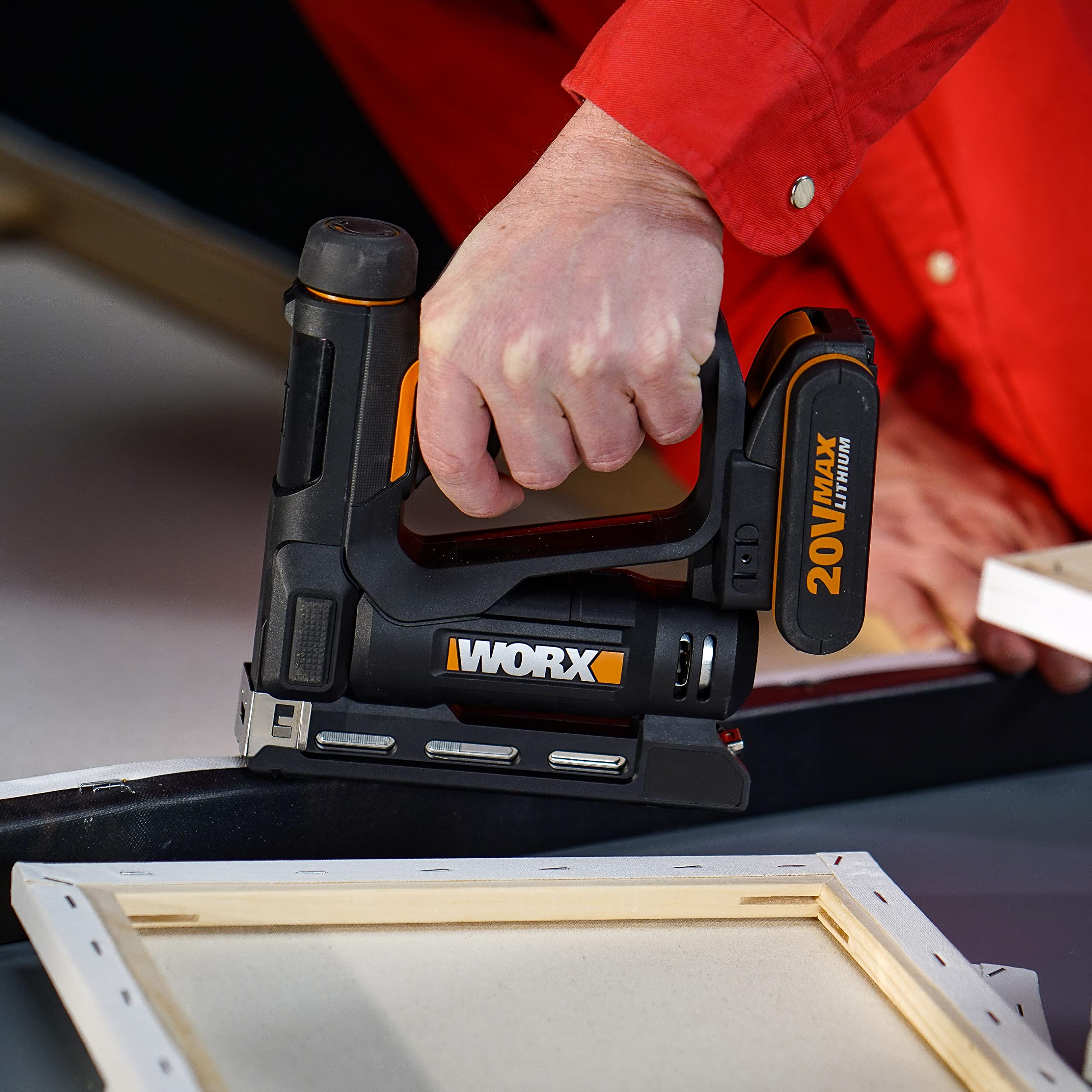 Eine Person im roten Hemd benutzt eine schwarze Worx-Akkutackerpistole für einen Holzrahmen.