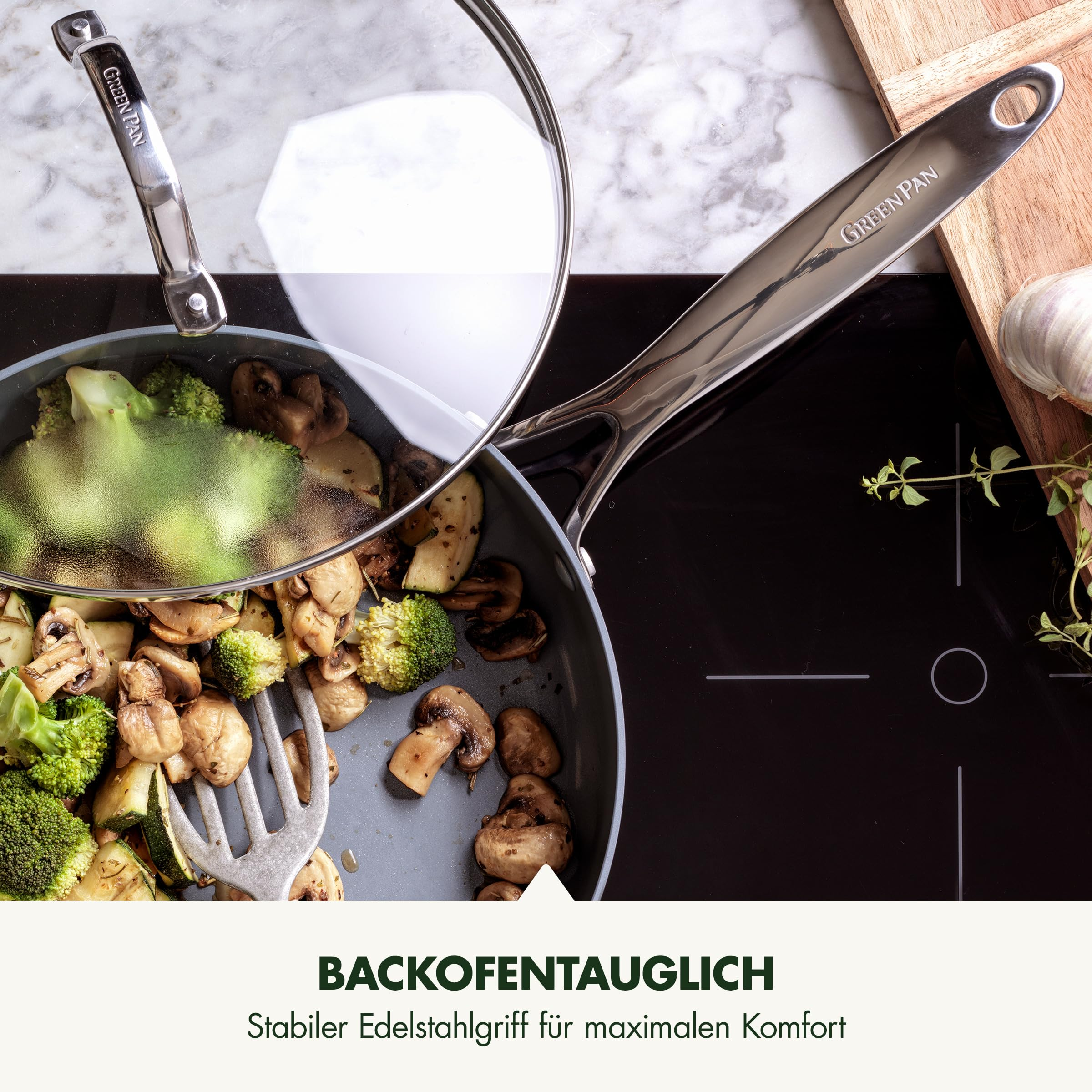 Une poêle GreenPan avec couvercle en verre sur une table de cuisson, remplie de légumes sautés.