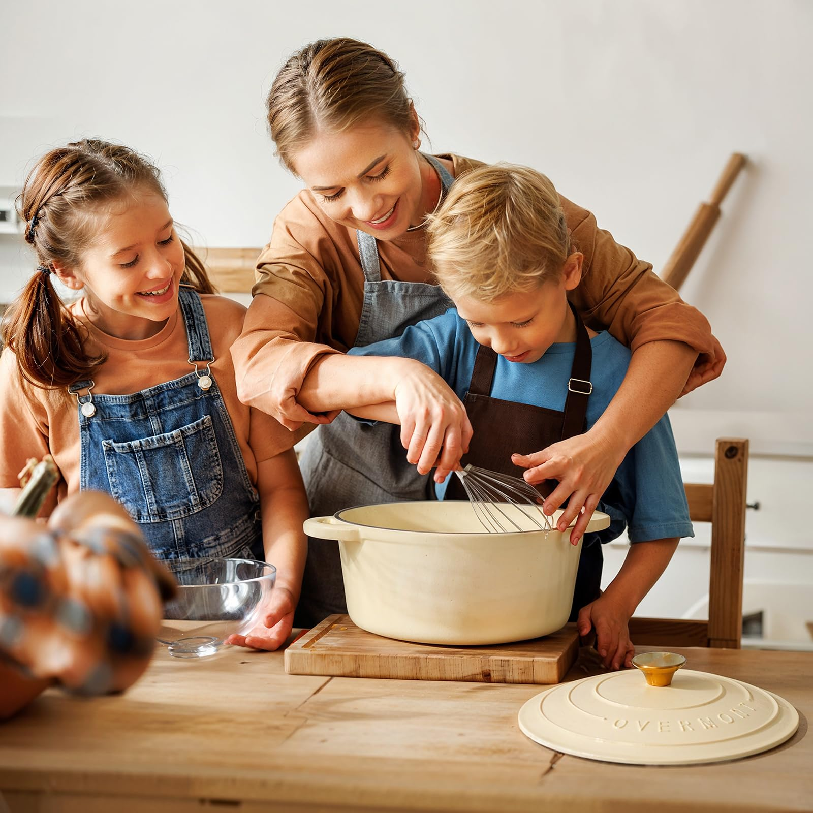 Una donna e due bambini cucinano insieme, mescolando con una frusta in una grande pentola.
