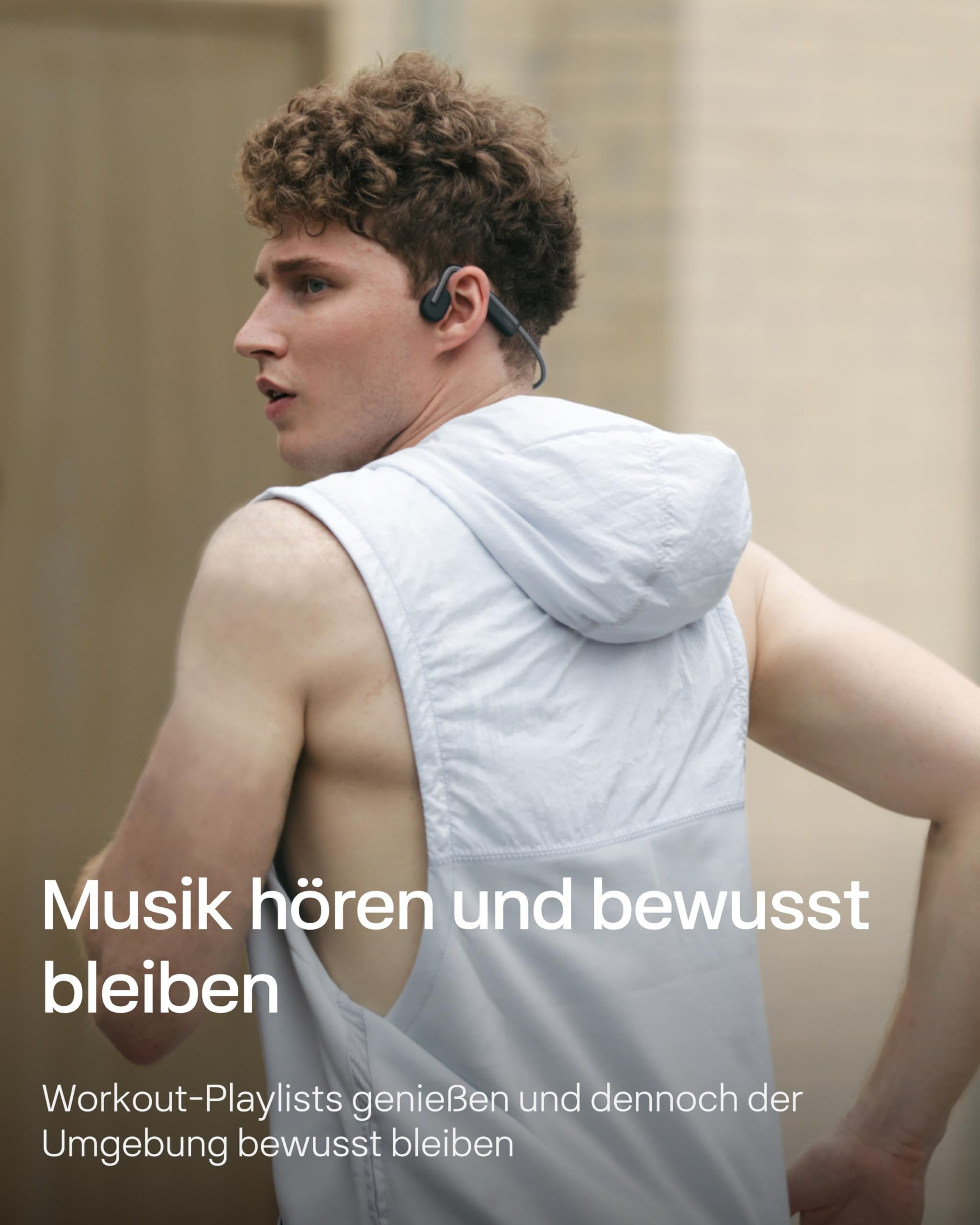 Ein Mann trägt einen hellblauen ärmellosen Hoodie und Knochenschall-Kopfhörer beim Laufen mit deutschem Text.