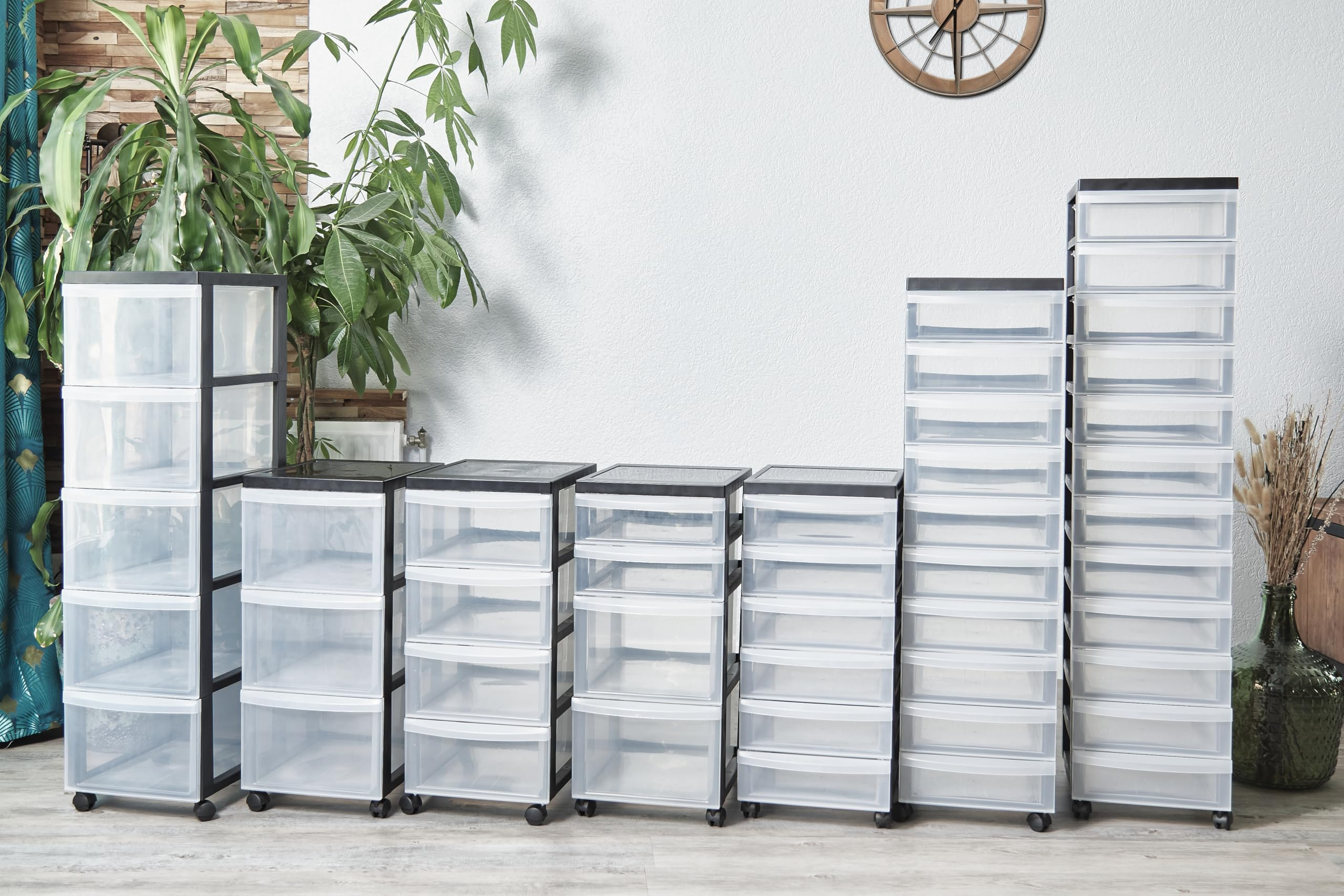 Verschiedene transparente Schubladenboxen auf Rollen stehen in einem Raum vor einer Wand.