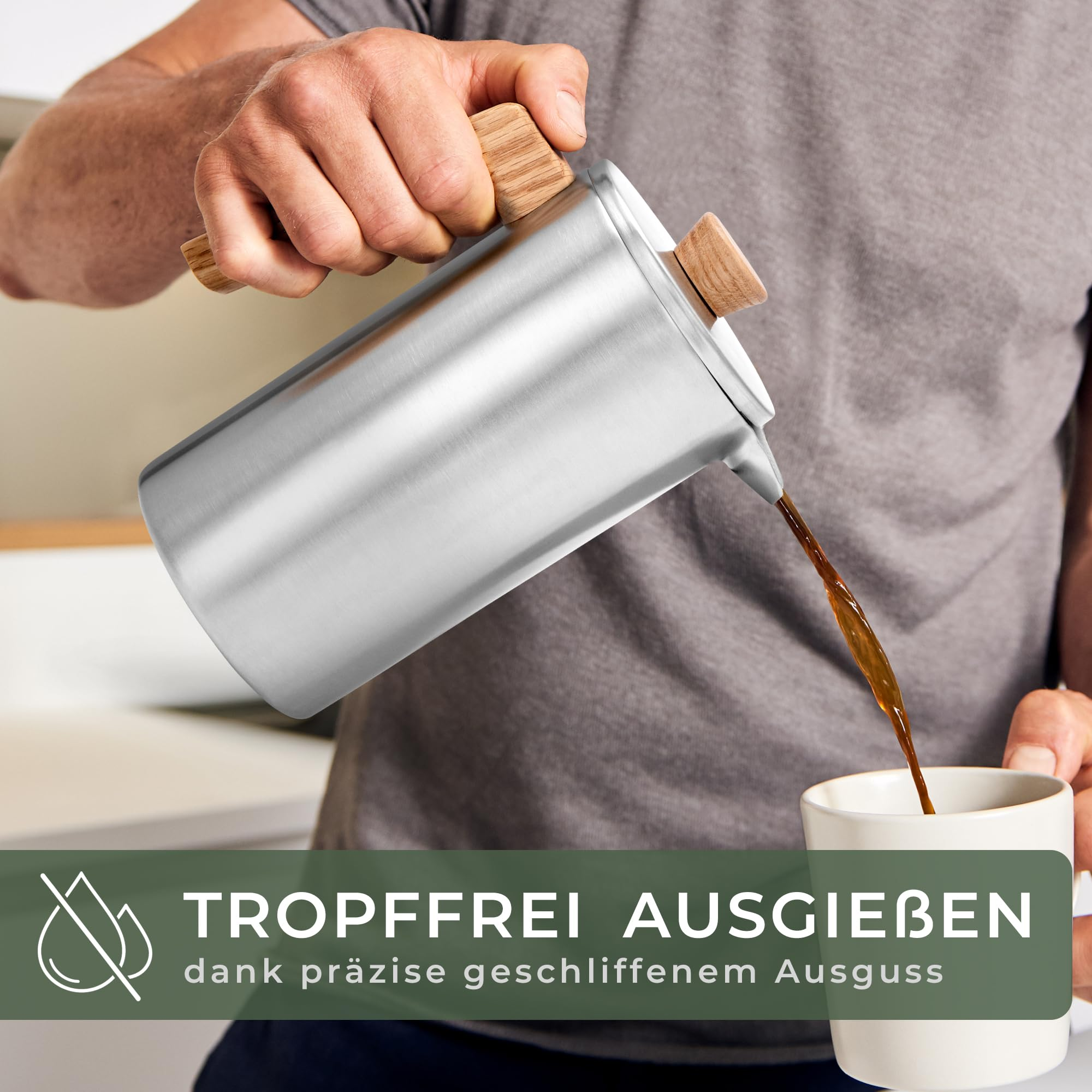 Eine Person gießt Kaffee aus einer Edelstahl-Kaffeekanne mit Holzakzenten in eine Tasse.