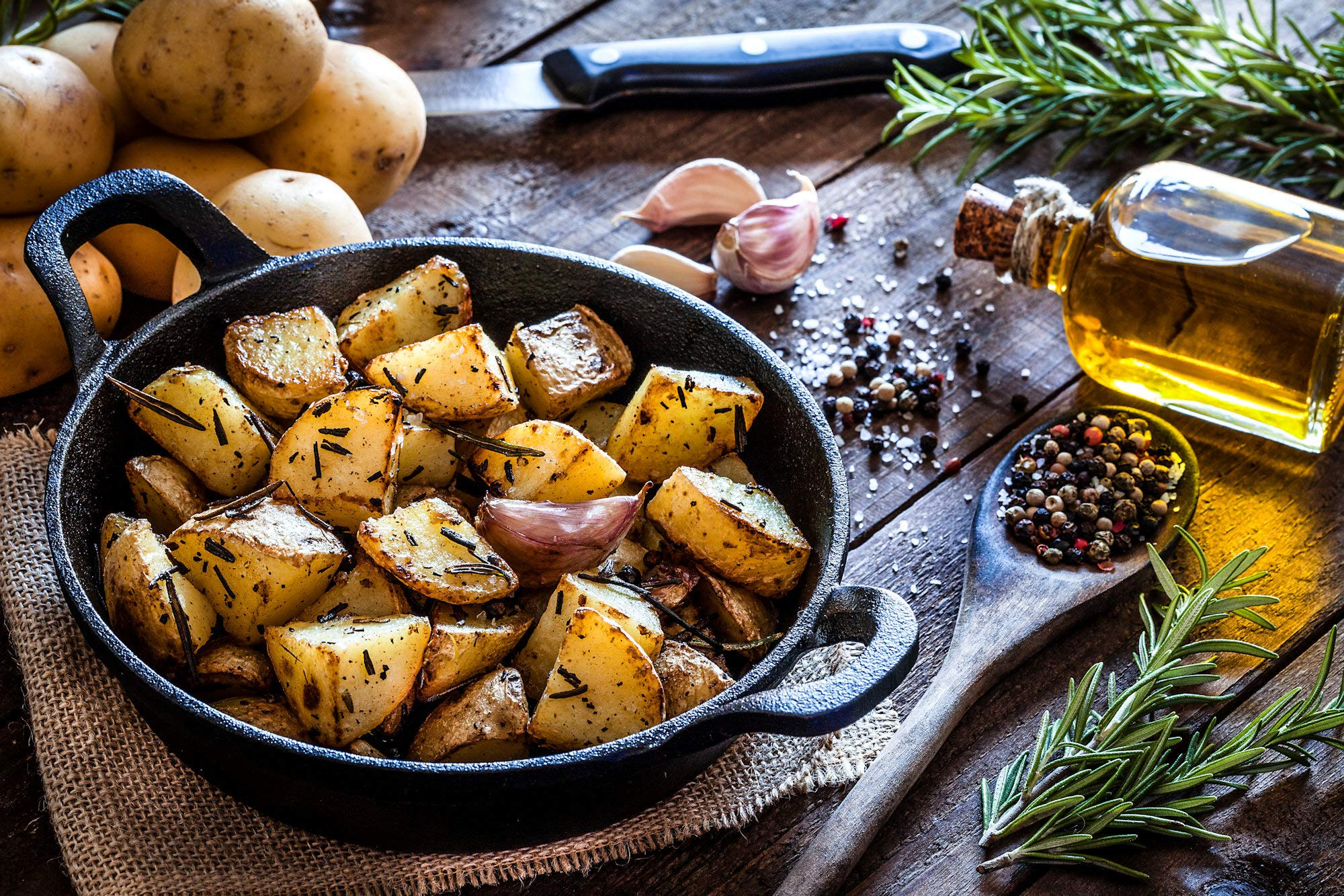 Pommes de terre rôties dans une poêle noire avec du romarin et des épices.