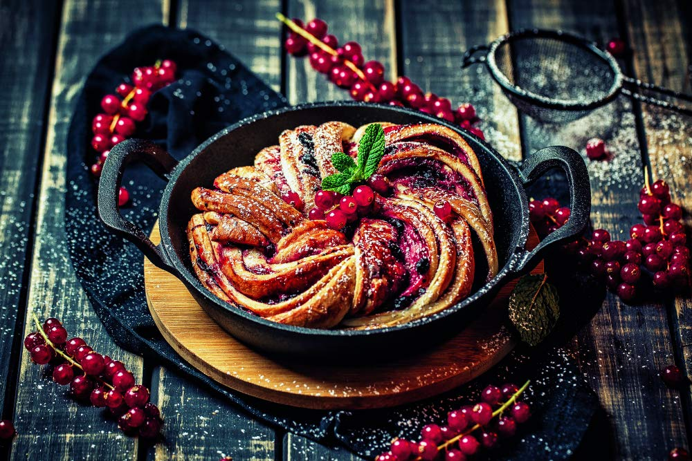 Gâteau fraîchement cuit avec des baies rouges dans une poêle en fonte.