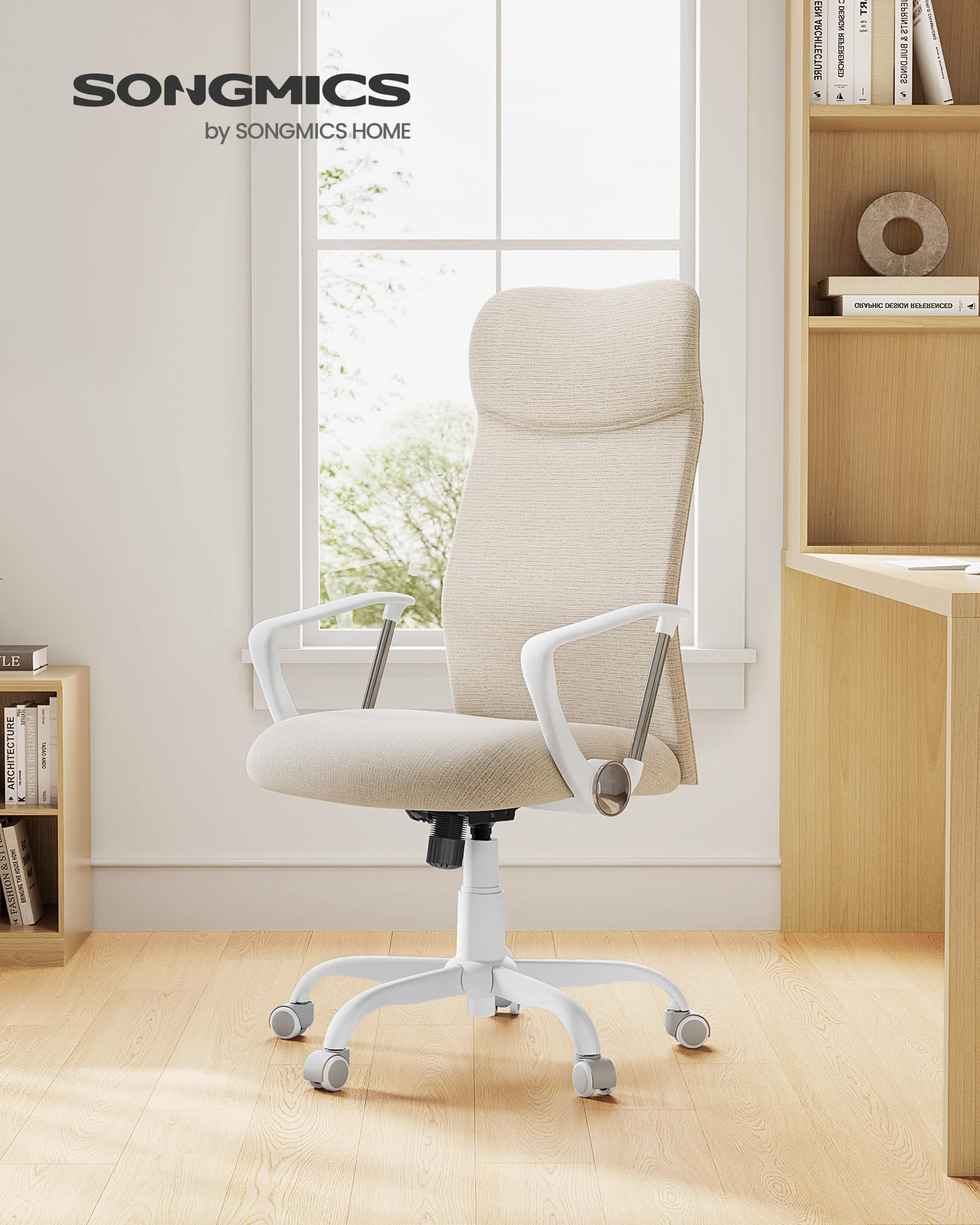 Une chaise de bureau beige avec des accoudoirs et une base blancs se trouve dans une pièce lumineuse devant une fenêtre.