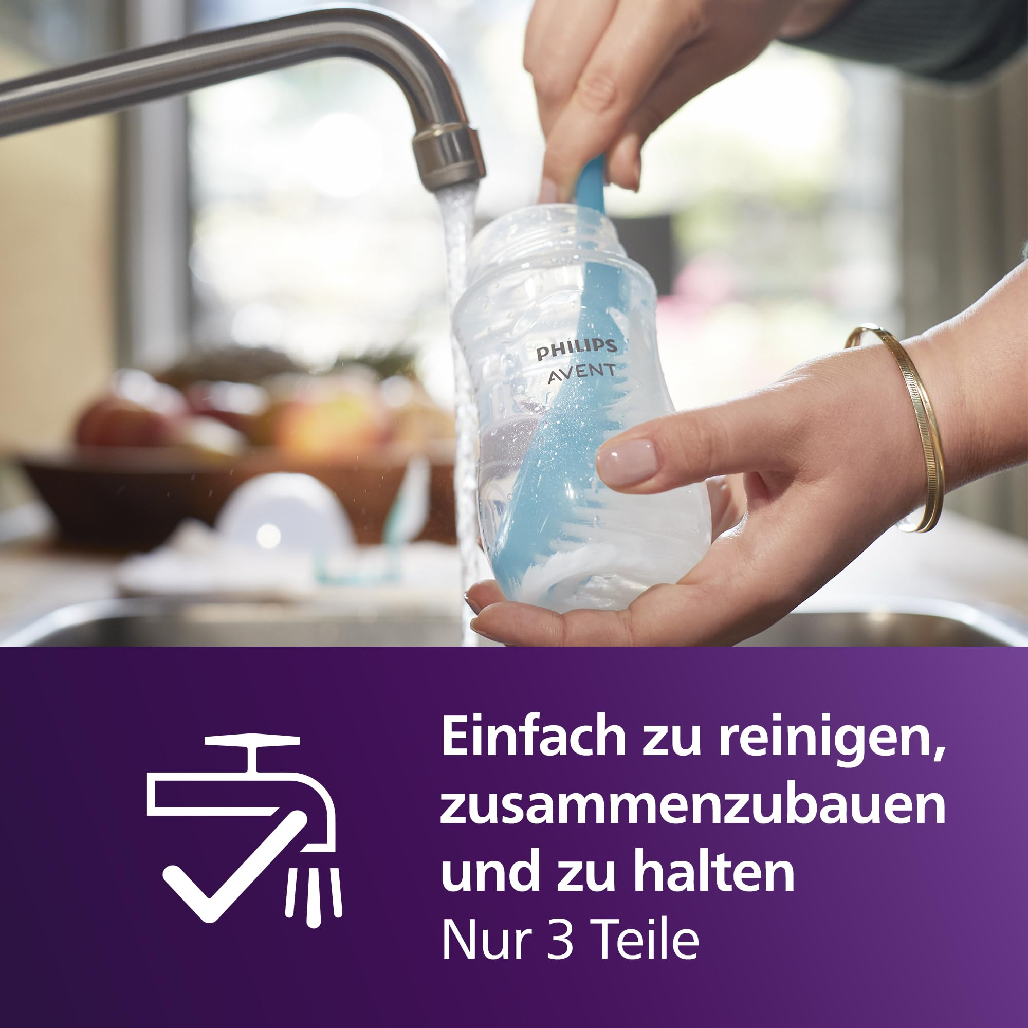 Una persona lava un biberon Philips Avent con uno spazzolino blu sotto il rubinetto.