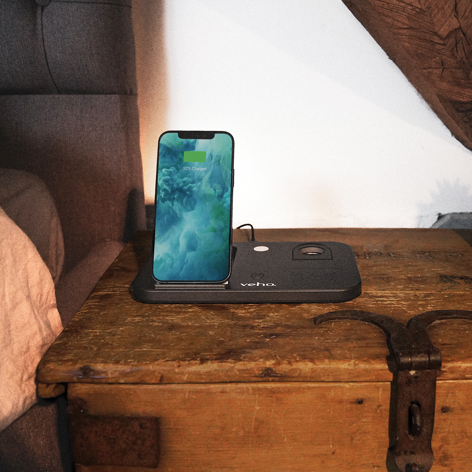 Ein Smartphone lädt auf einer schwarzen kabellosen Ladestation auf einem rustikalen Nachttisch.