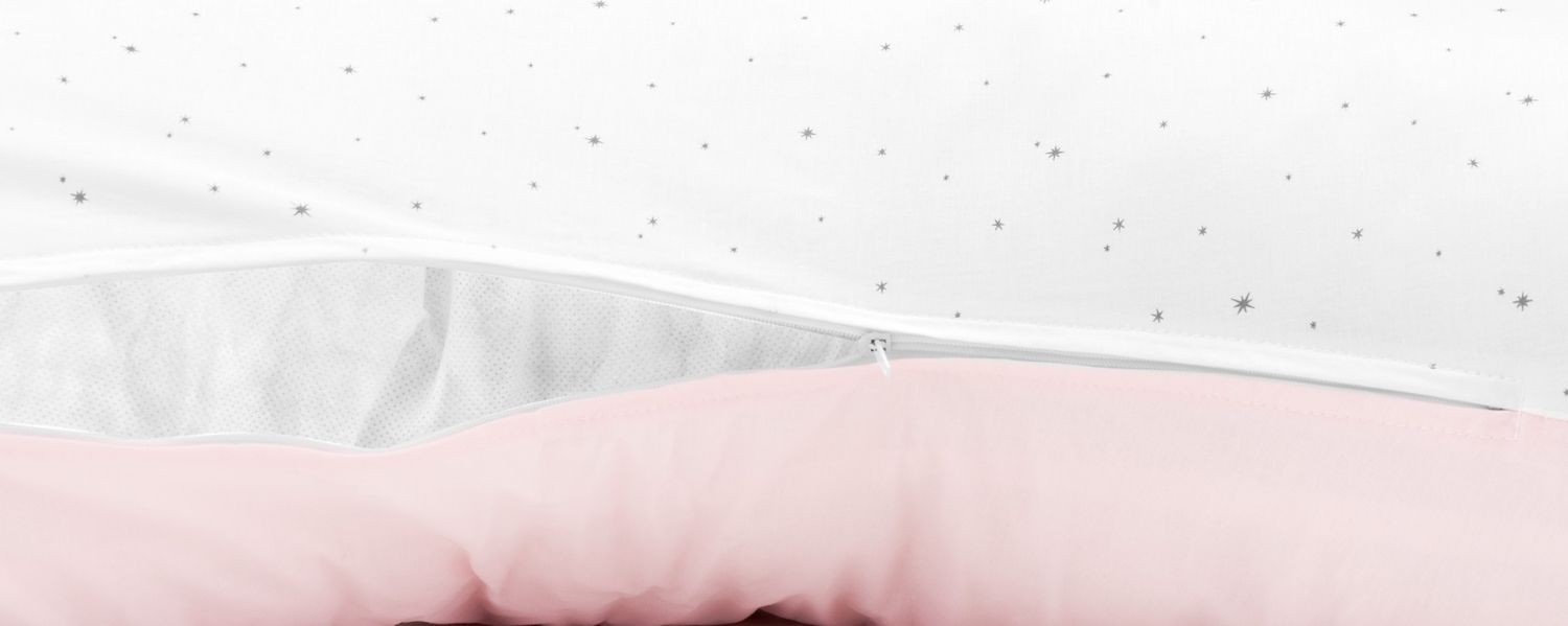 Weisser Stoff mit grauen Sternen und Reissverschluss, der rosa Kissen enthüllt.