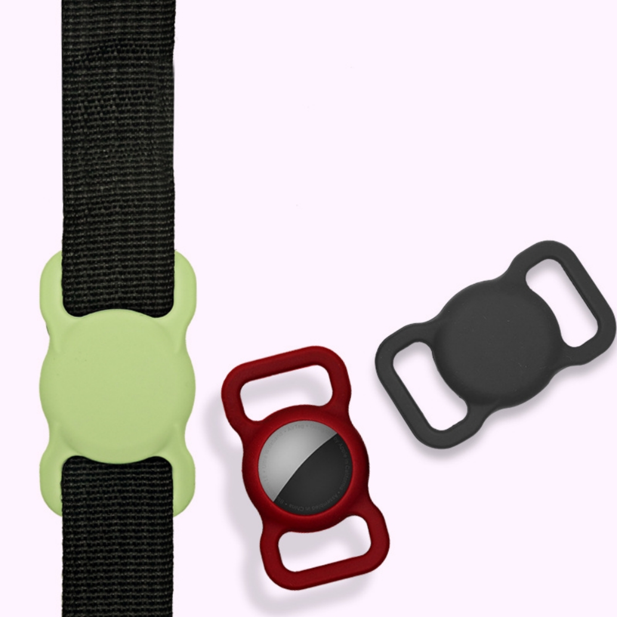 Ein schwarzer Riemen mit hellgrünem Halter, daneben ein roter Halter mit AirTag und ein schwarzer.