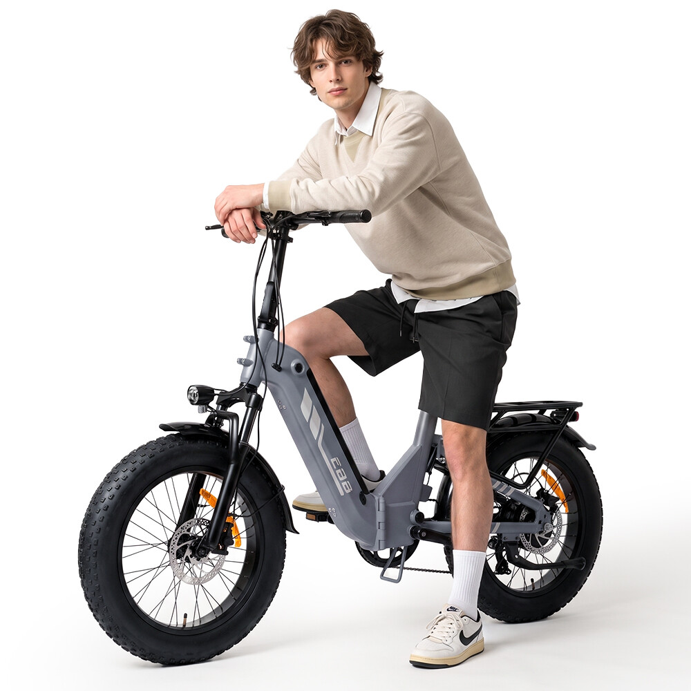 Ein junger Mann sitzt auf einem grauen E-Bike vor weißem Hintergrund und blickt in die Kamera.