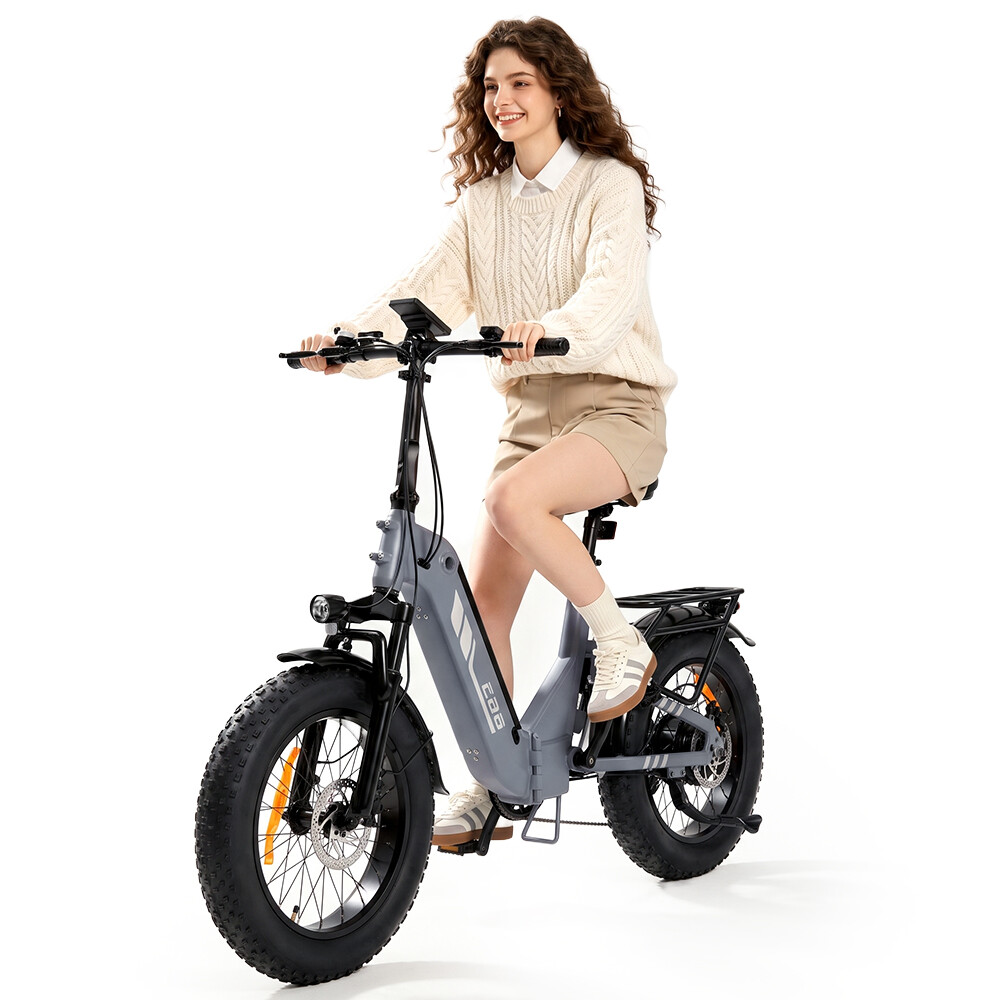 Eine lächelnde Frau fährt auf einem grauen Elektrofahrrad mit dicken Reifen vor weißem Hintergrund.
