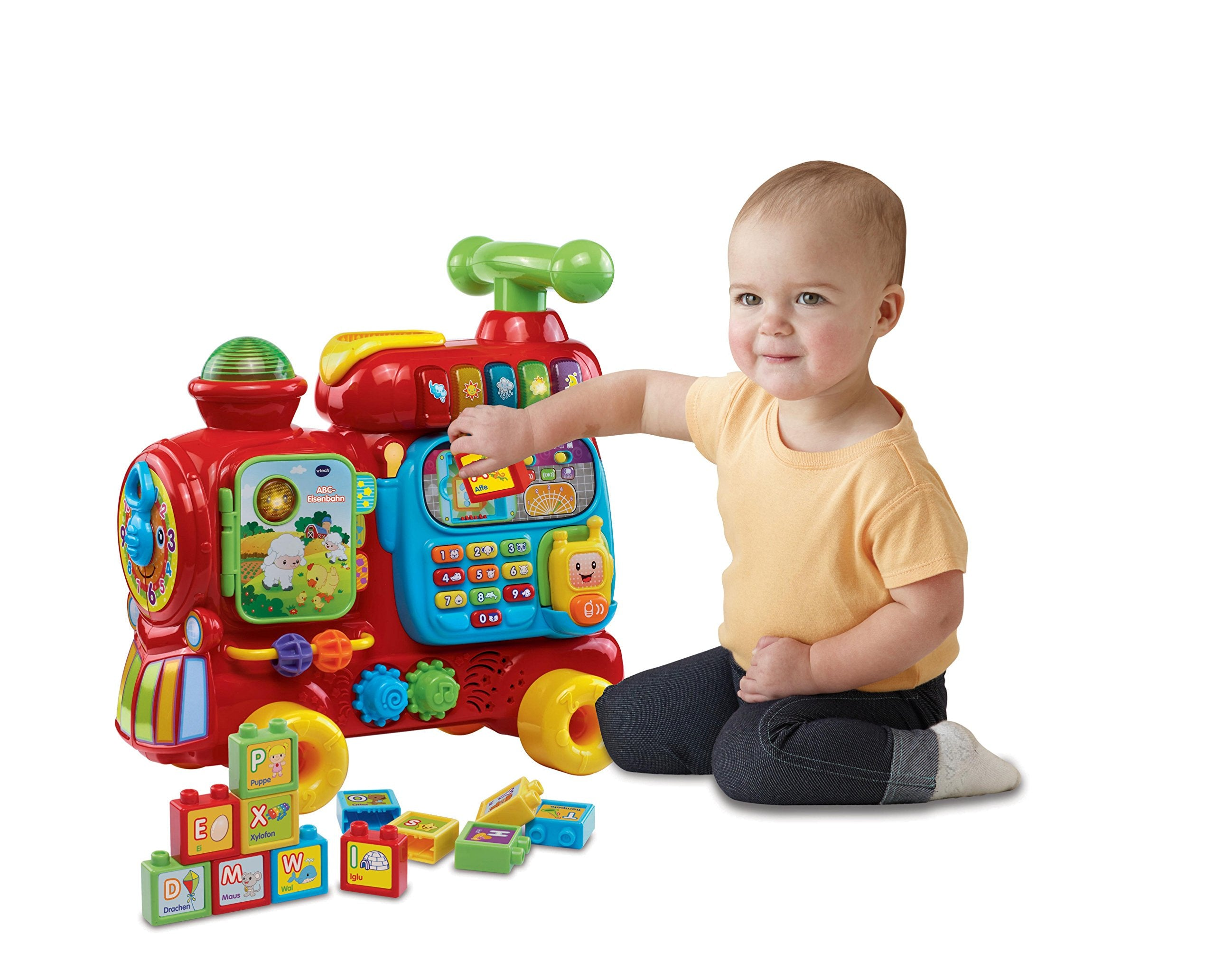 Ein Baby sitzt und spielt mit einem bunten Spielzeugeisenbahn mit Buchstabenblöcken.