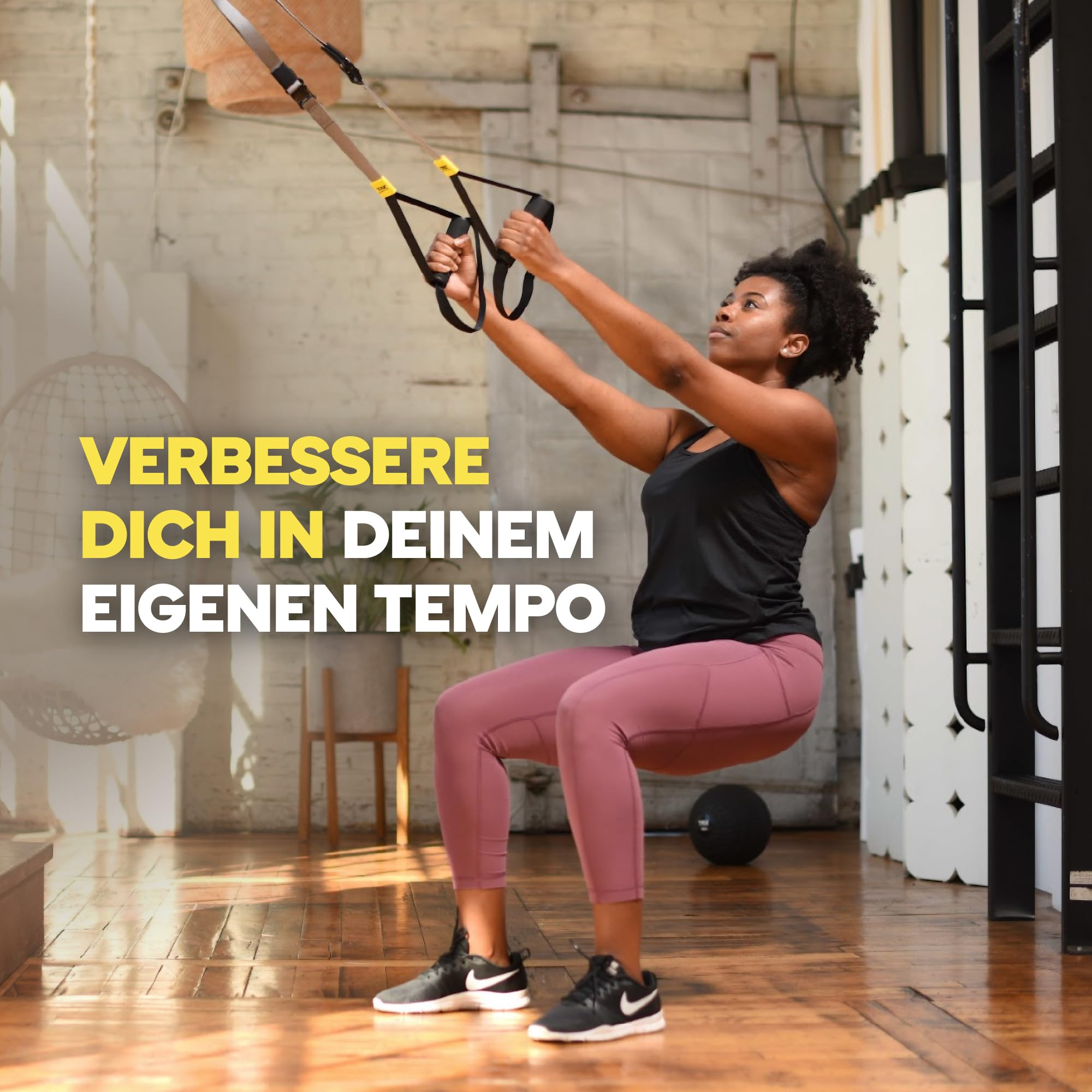 Una donna in abbigliamento sportivo fa squat usando cinghie di sospensione in studio.