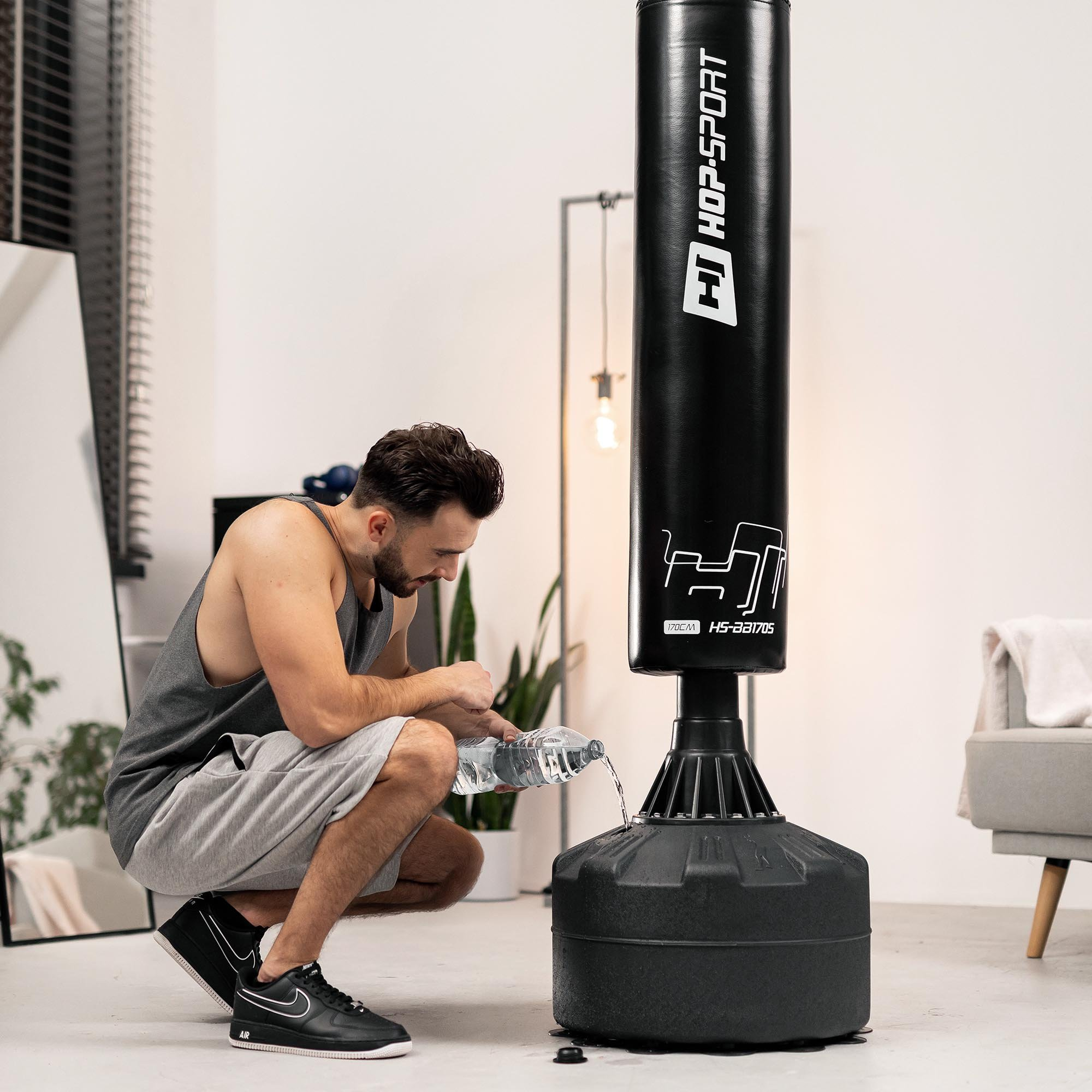 Ein Mann füllt Wasser in den Sockel eines schwarzen Standboxsacks.
