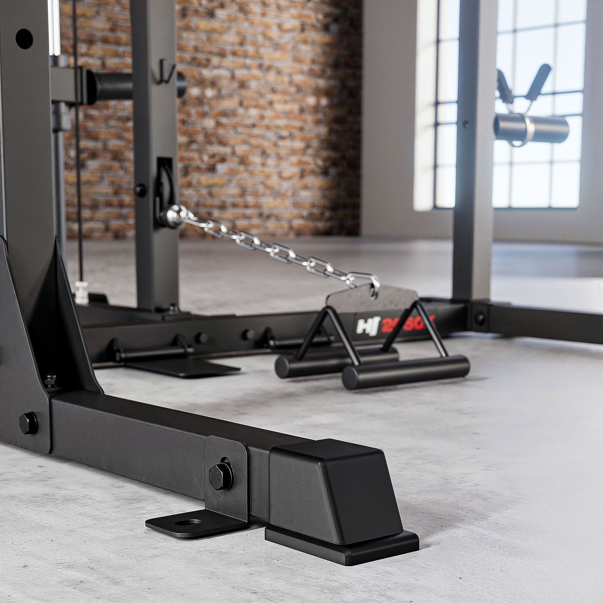 Nahaufnahme eines schwarzen Fitness-Power-Racks mit Metallketten und Griffen auf einem Betonboden.