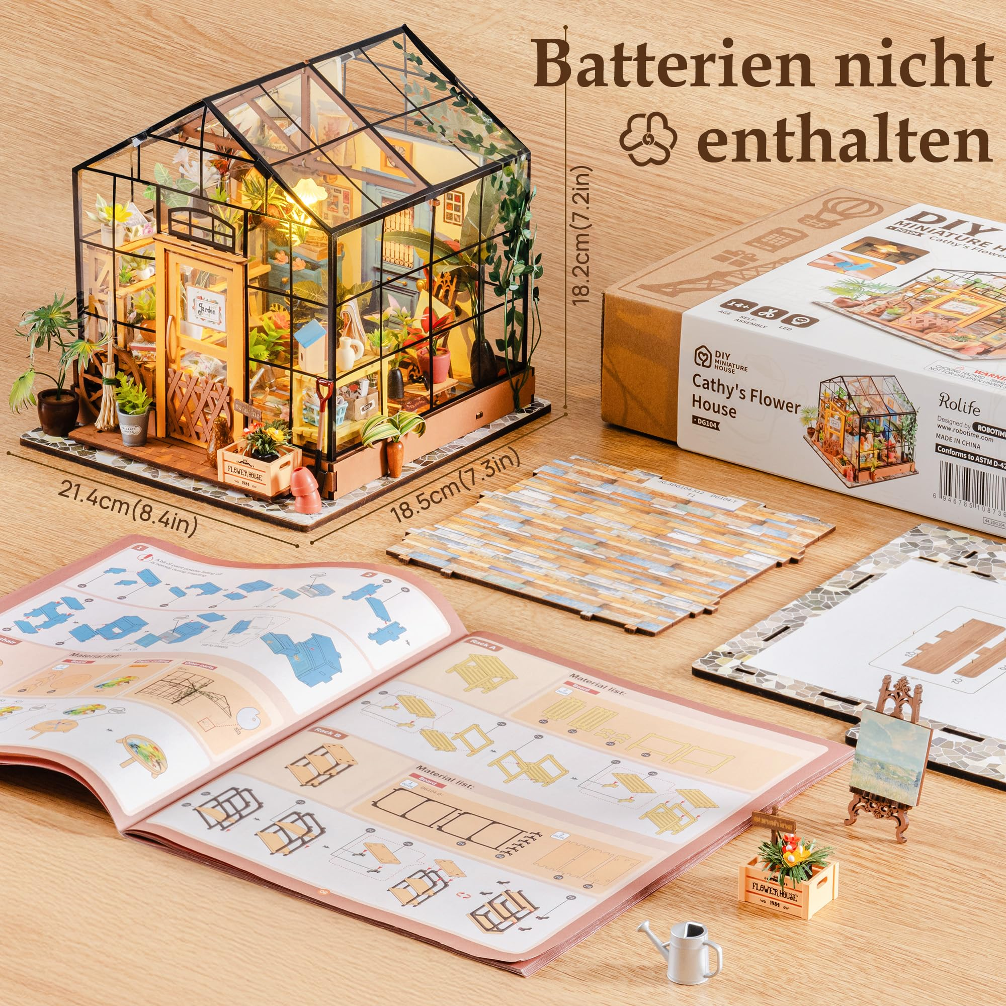Ein DIY-Gewächshaus-Miniaturbausatz mit Anleitung, Verpackung und Teilen auf einem Holztisch.