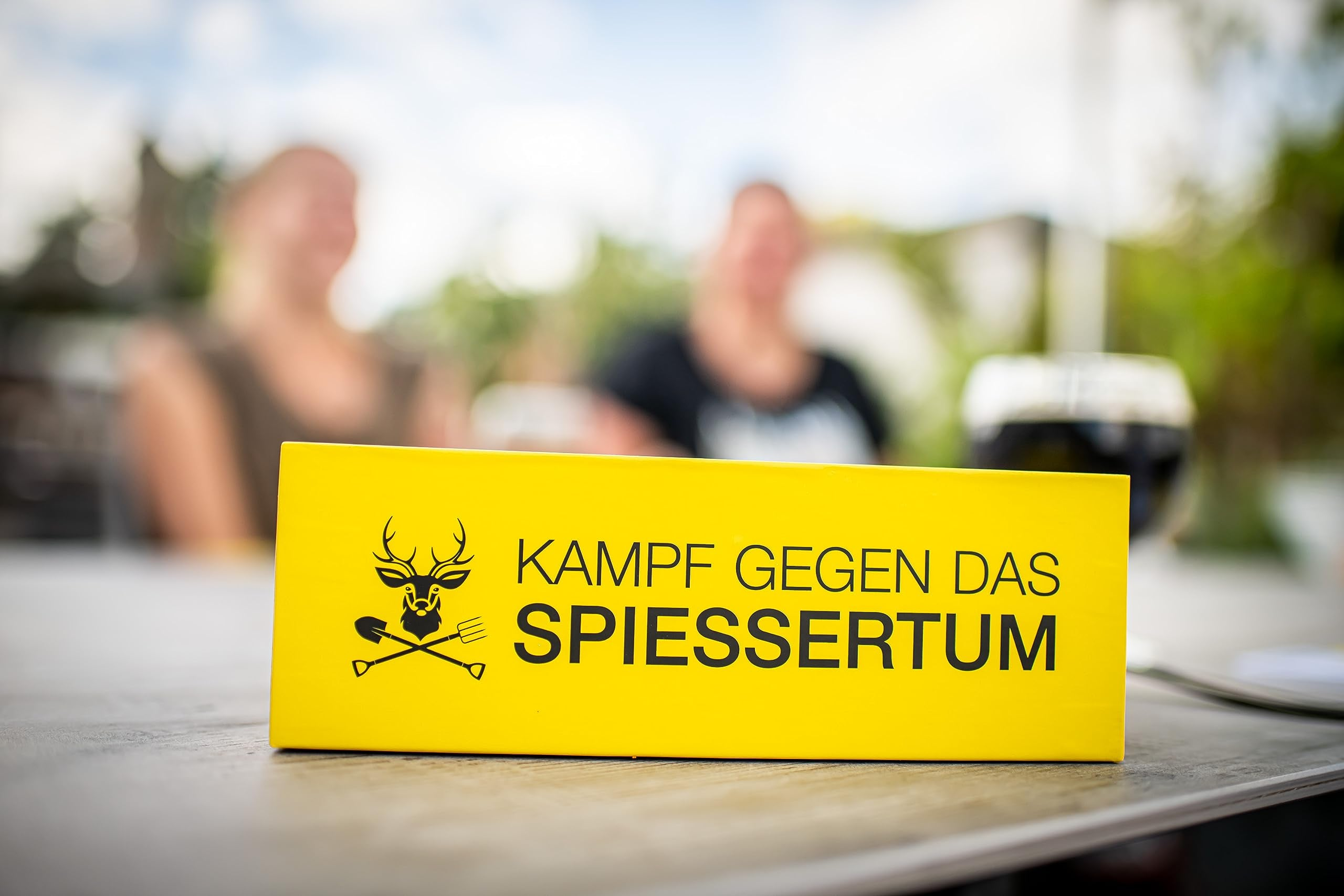 Panneau jaune avec du texte noir et un logo de cerf sur une table.