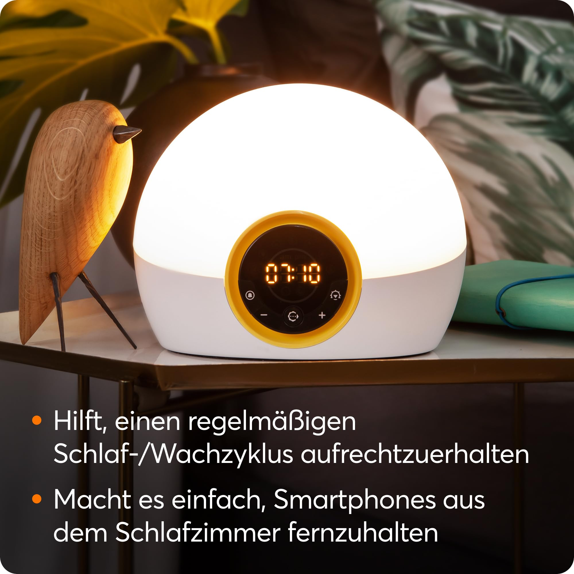 Beleuchteter runder Wecker mit Holzvogel und Text auf weißem Tisch.