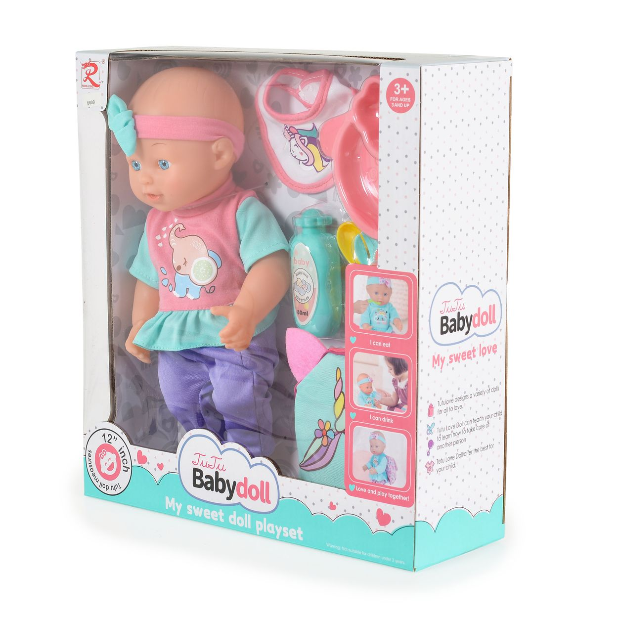 Eine verpackte Puppe in rosa und türkiser Kleidung, mit Latz, Fläschchen und Zubehör in einer bunten Schachtel.