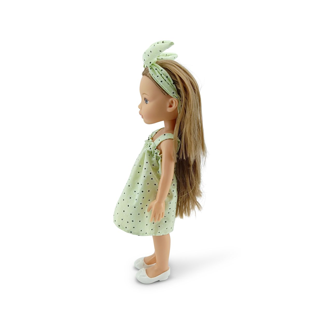 Eine blonde Puppe im Profil trägt ein hellgrünes Kleid mit Blumenmuster, ein passendes Stirnband und weiße Schuhe.
