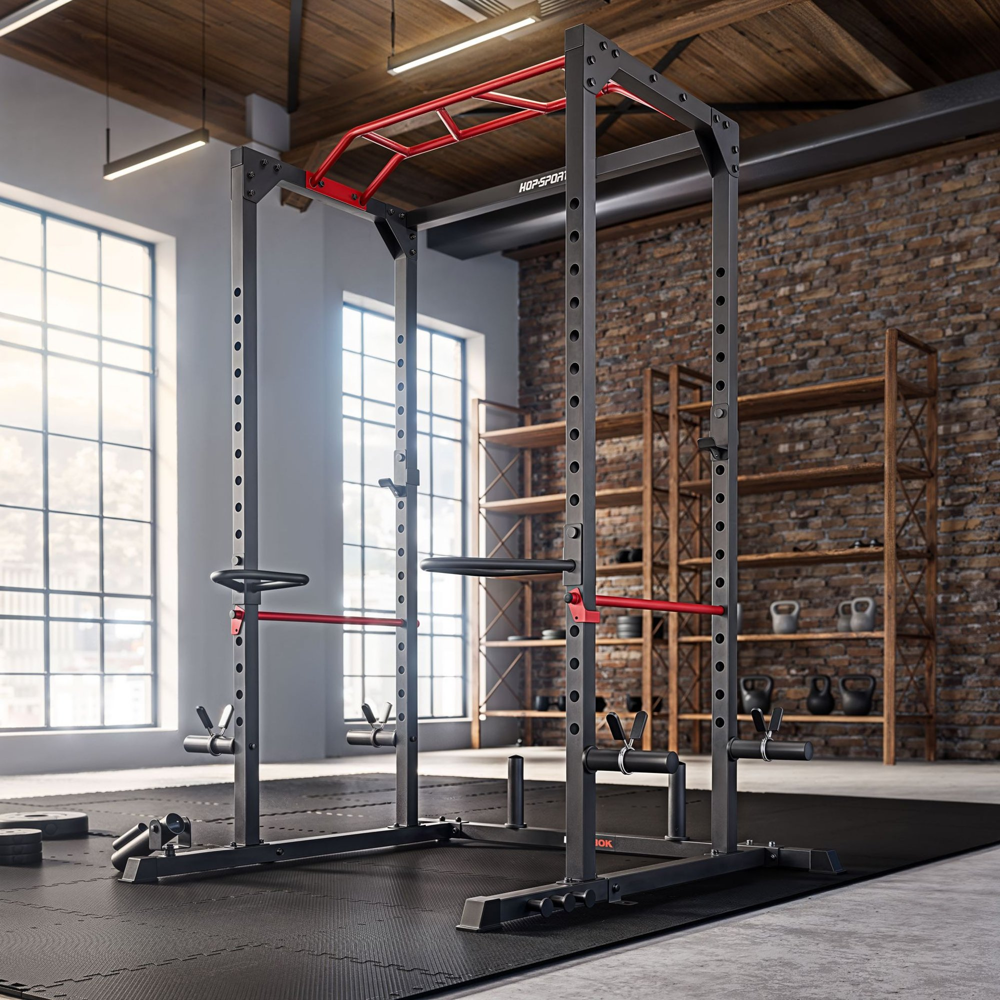 Ein schwarzes Power-Rack mit roten Akzenten steht in einem Fitnessstudio mit Ziegelwand und großen Fenstern.