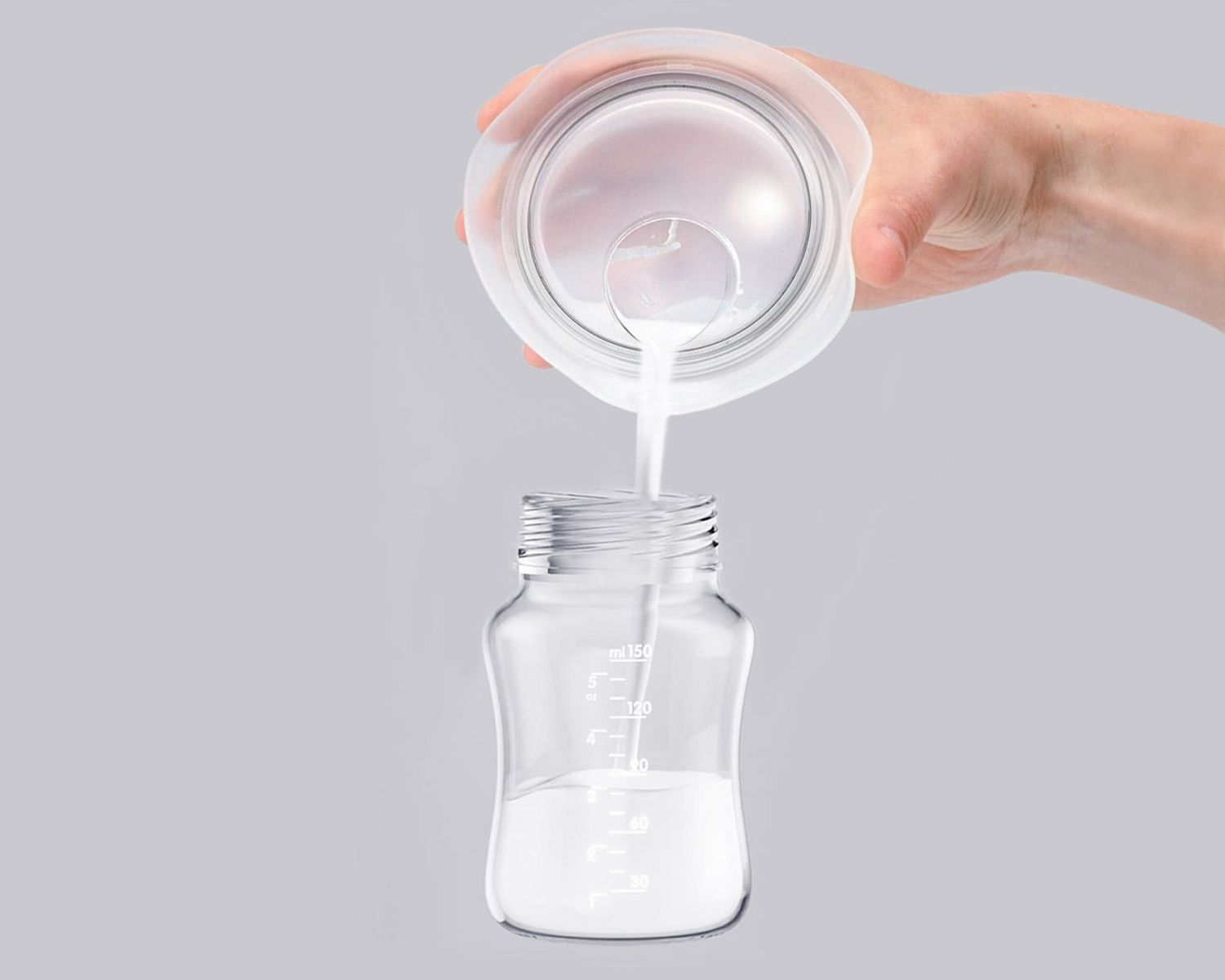 Milch wird aus einem Kunststoffbehälter in eine Babyflasche gegossen.