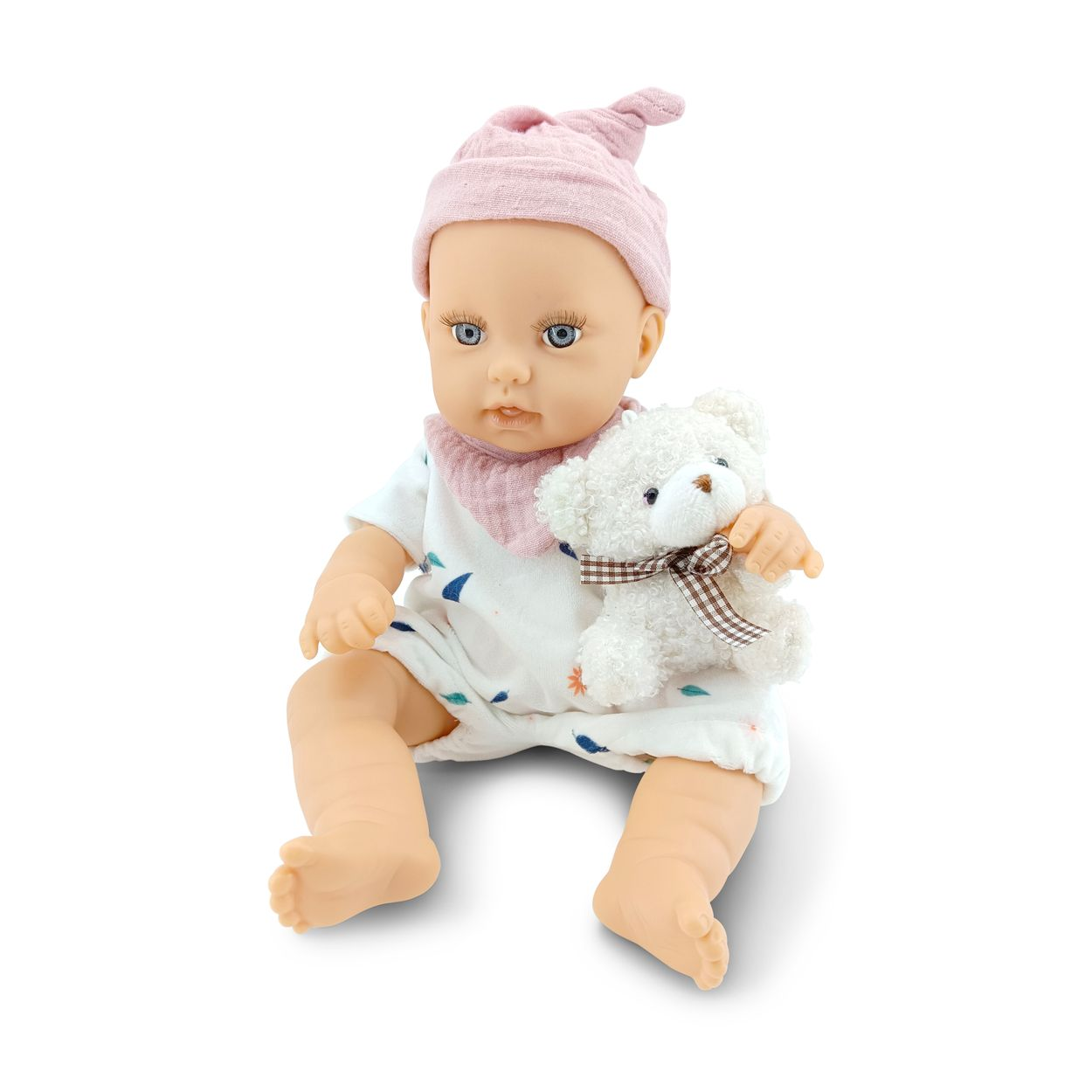 Eine sitzende Babypuppe mit rosa Mütze, weißem Strampler und einem kleinen weißen Plüschbären auf weißem Hintergrund.