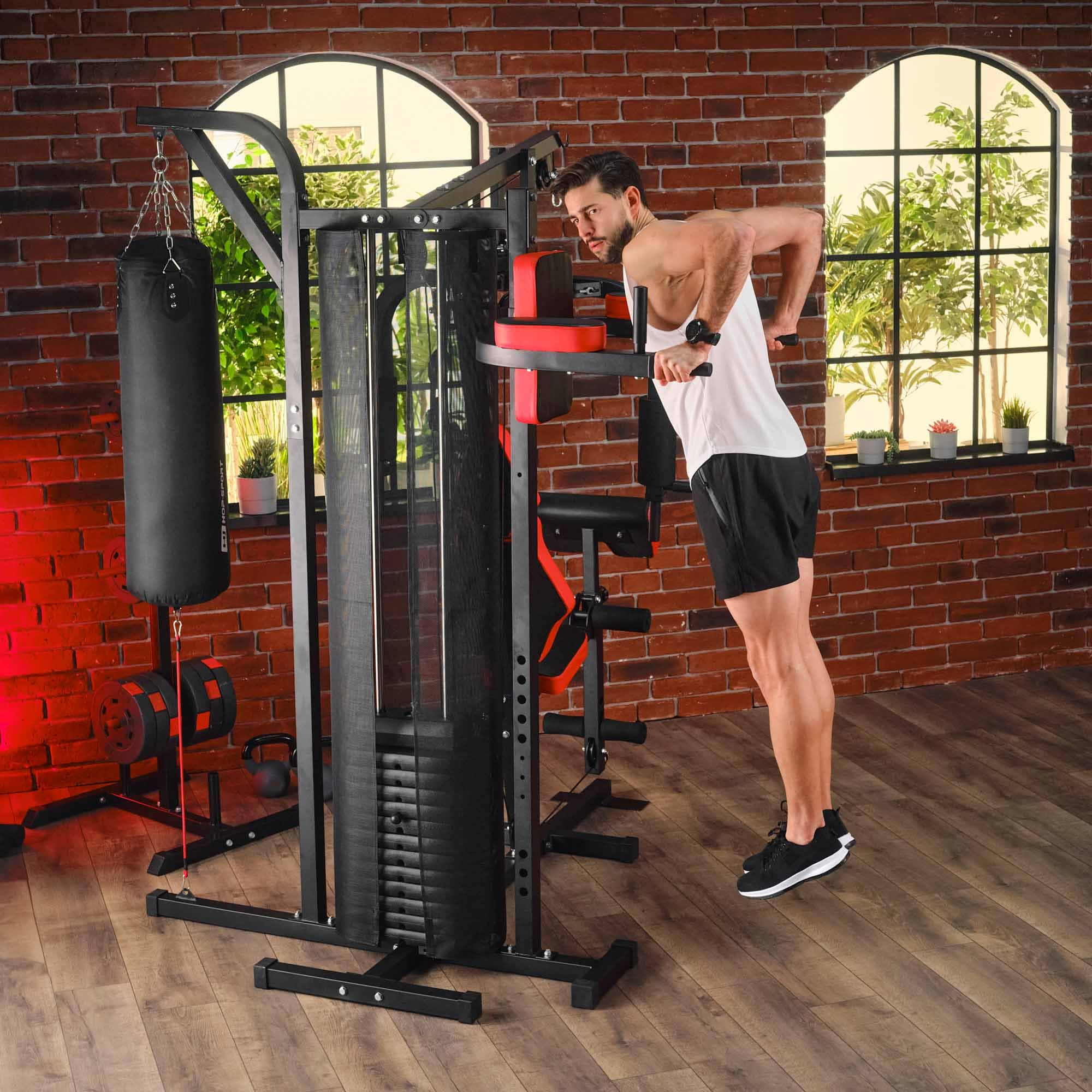 Ein Mann in Sportkleidung macht Dips an einer Multifunktions-Kraftstation im Fitnessraum.