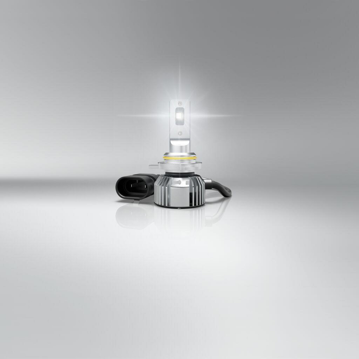 Eine leuchtende LED-Scheinwerferlampe auf glatter, grauer Oberfläche mit einem Stromanschluss.