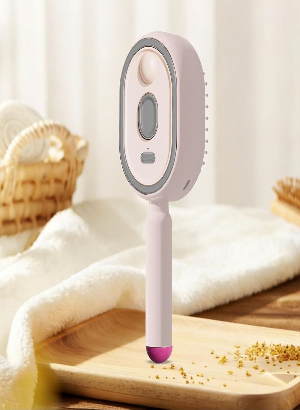 Eine rosa elektronische Handbürste für Haustiere steht auf einem Holztablett mit einem Handtuch und einem Korb.