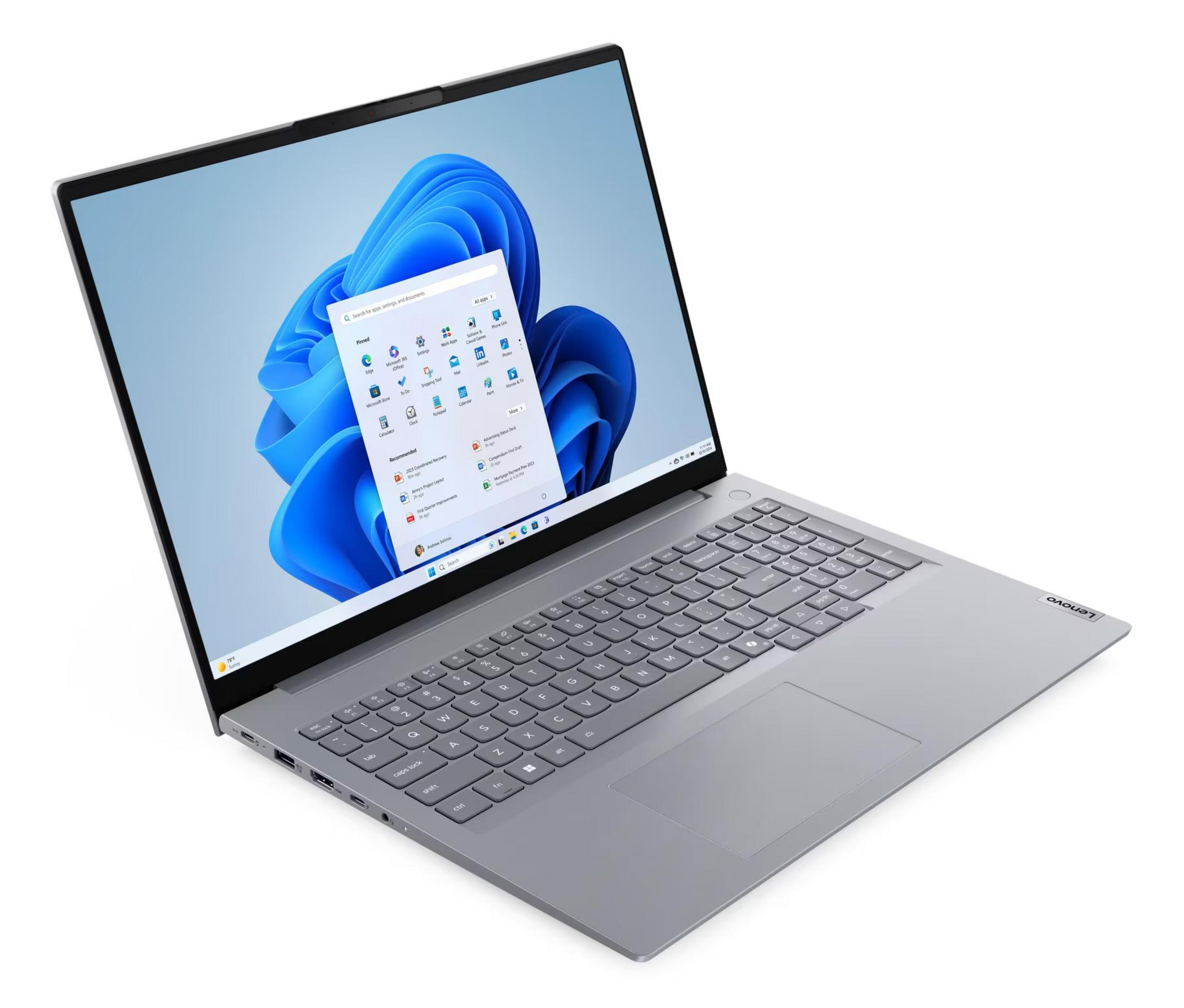 Srebrny laptop z otwartym ekranem wyświetla niebieskie menu startowe systemu Windows 11 na białym tle.