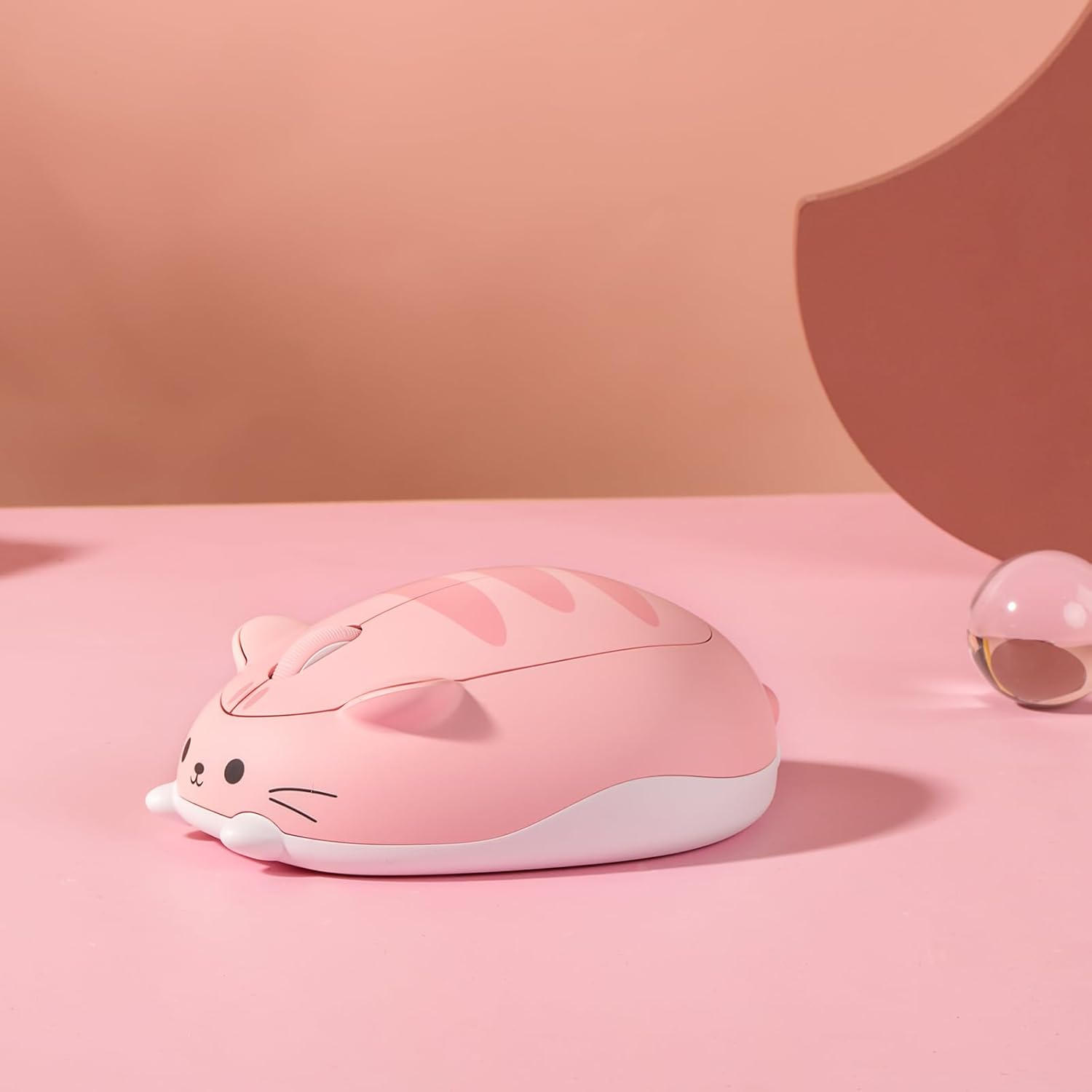 Pembe bir zeminde duran, kedi şeklinde sevimli pembe bir bilgisayar faresi.