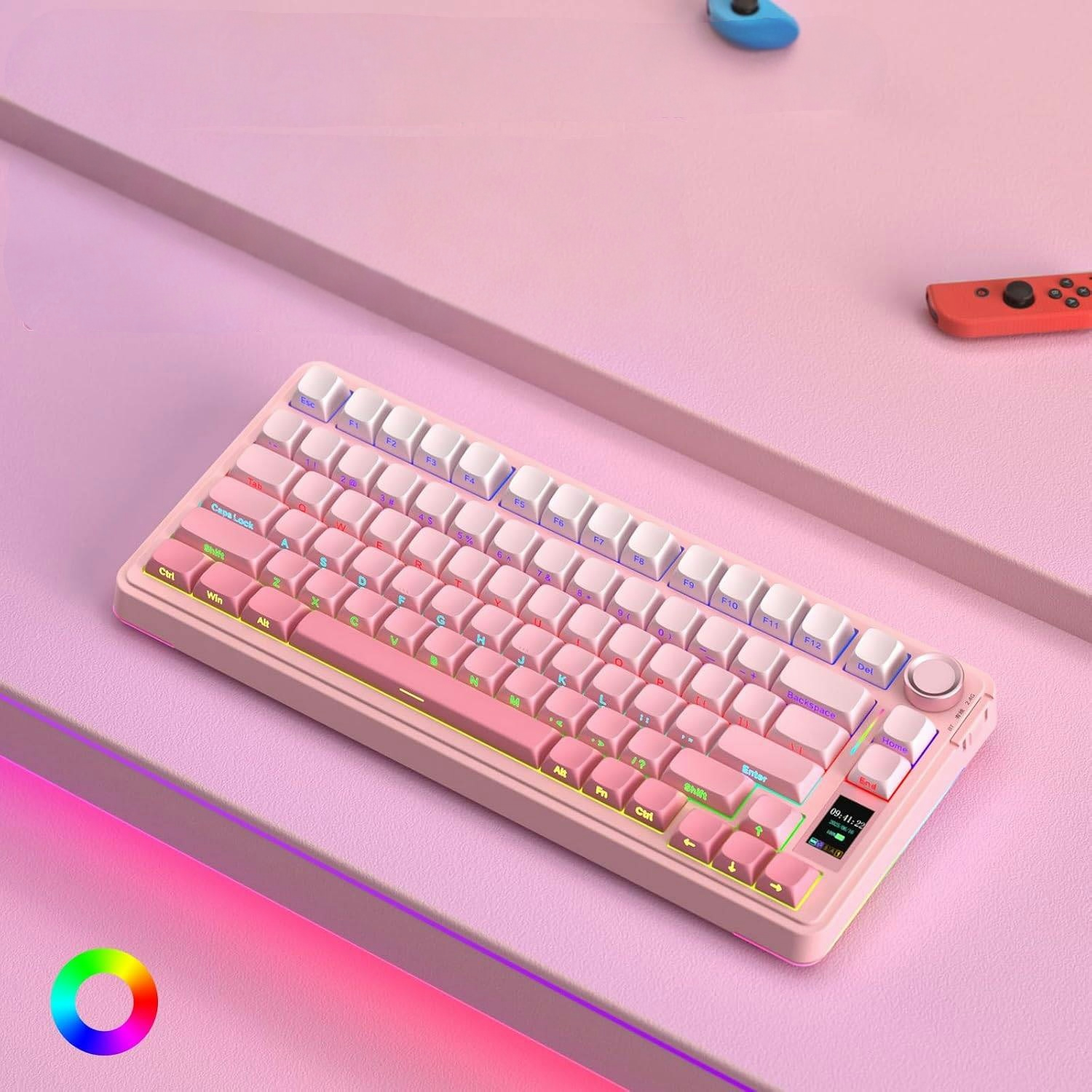 Różowo-biała klawiatura mechaniczna z oświetleniem RGB na różowym biurku, z kontrolerami do konsoli w tle.