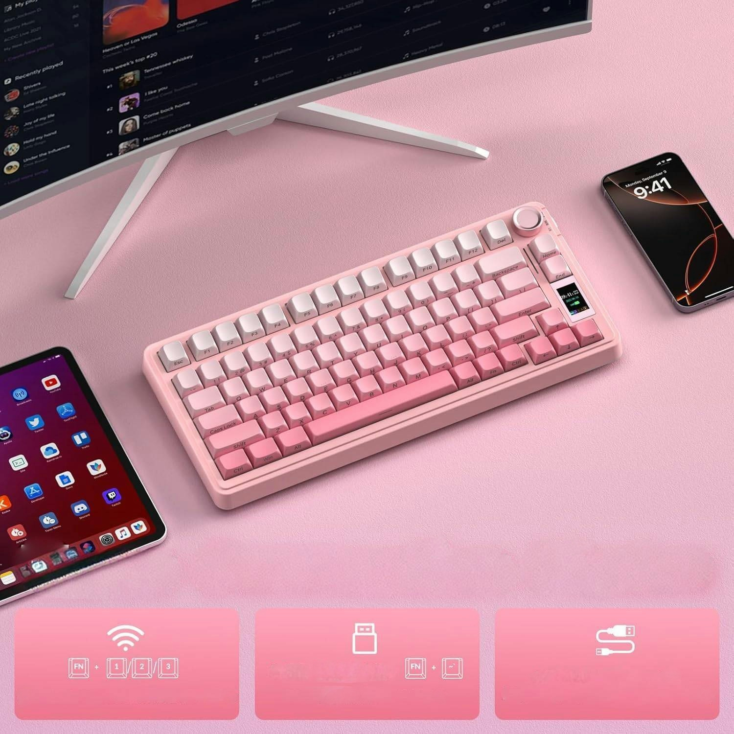 Różowy zestaw biurkowy z różową klawiaturą, tabletem, smartfonem i monitorem na różowym tle.