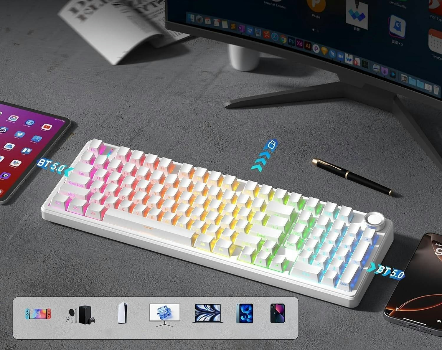 Biała klawiatura mechaniczna z podświetleniem RGB na biurku z monitorem, tabletem i długopisem.