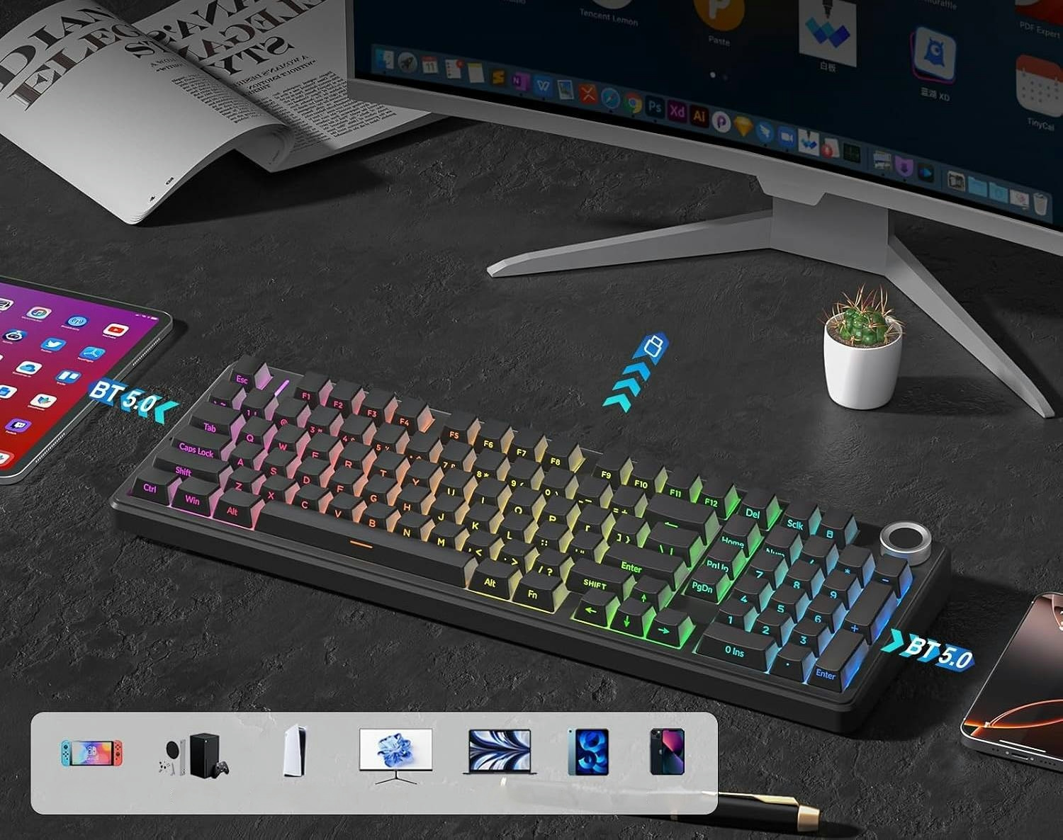 Mechaniczna klawiatura z oświetleniem RGB na ciemnym biurku z monitorem, tabletem i książką.