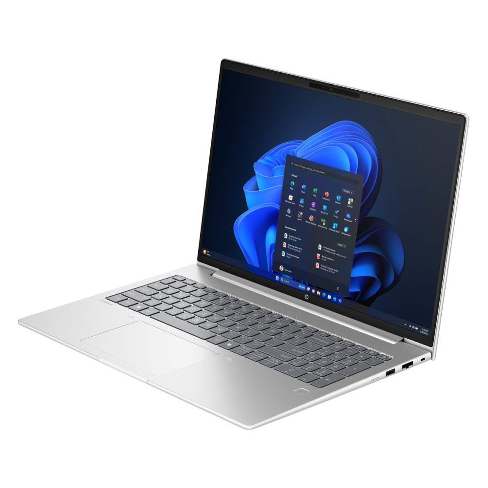 Srebrny laptop jest otwarty na białej powierzchni, wyświetlając niebieskie kwiatowe tło pulpitu.