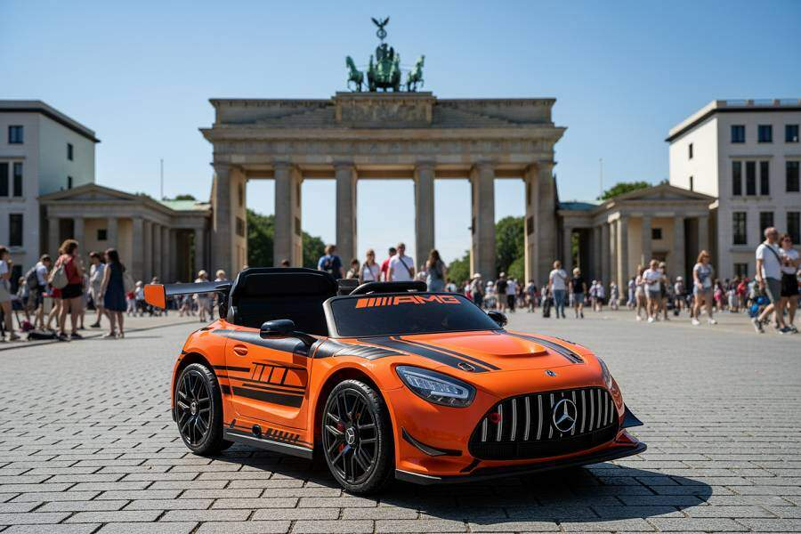 Ein orangefarbenes Spielzeugauto auf einem Platz in Berlin vor dem Brandenburger Tor mit Menschen im Hintergrund.