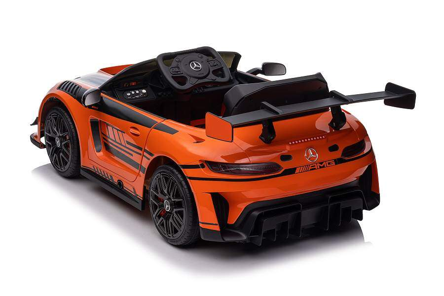 Ein orangefarbenes Mercedes-AMG Kinderauto mit schwarzem Spoiler und Felgen auf weißem Grund.