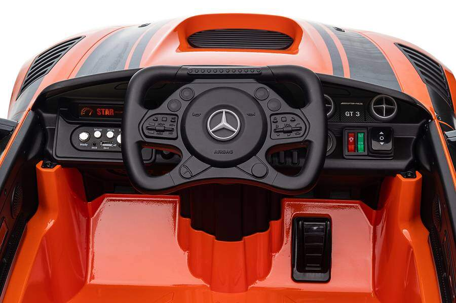 Innenraum eines orangefarbenen Spielzeugautos mit schwarzem Lenkrad und Armaturenbrett.
