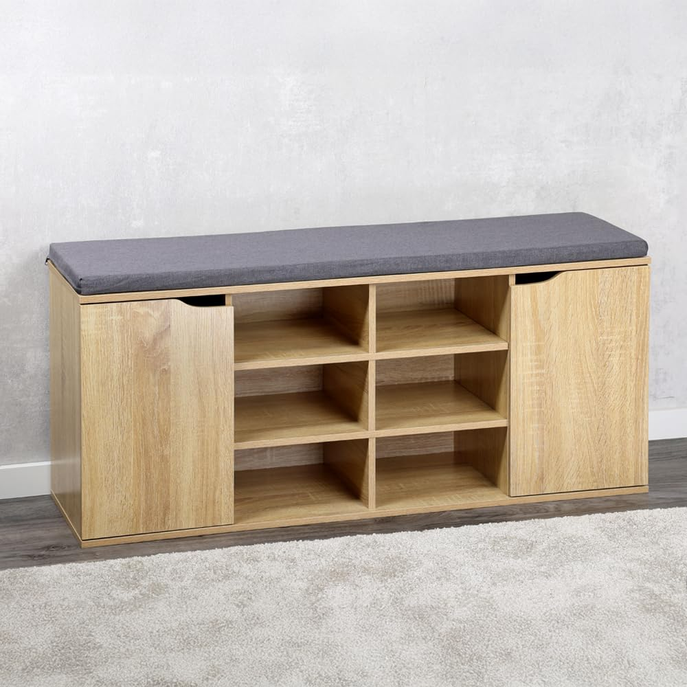 Holzschuhbank mit sechs offenen Fächern, zwei Türen und einem grauen Sitzkissen auf einem Teppich.