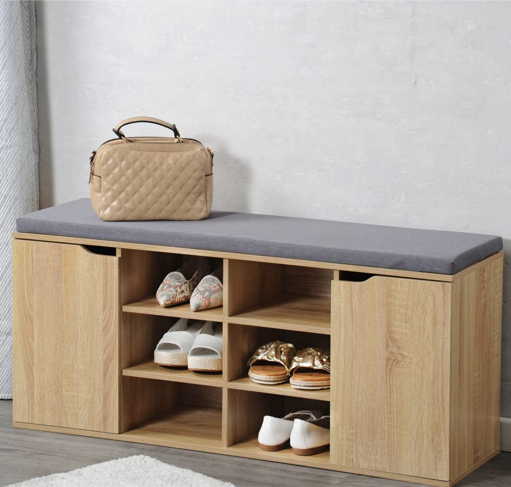 Holzschuhbank mit grauem Kissen, Schuhen und einer beigen Handtasche.