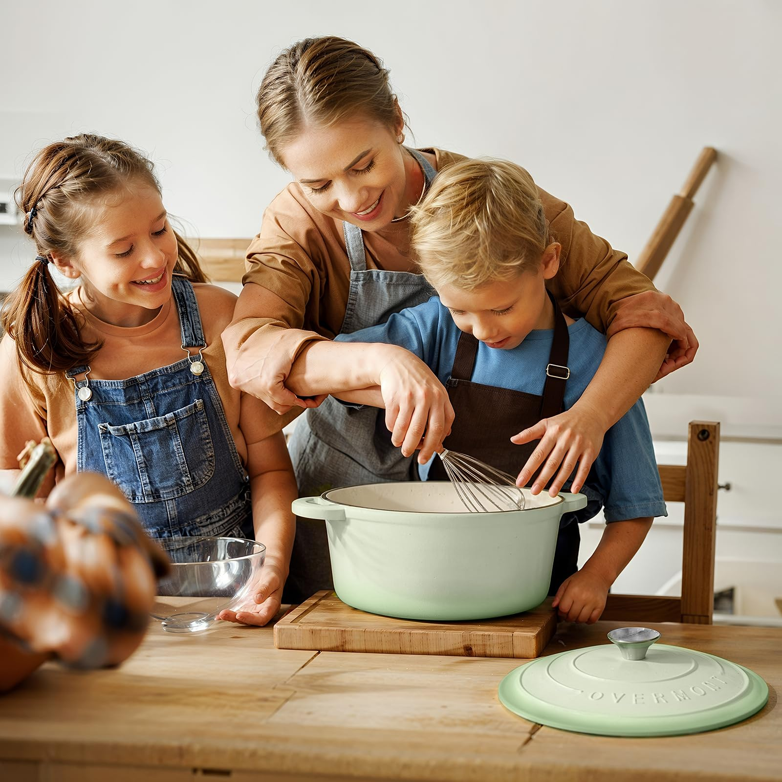 Una donna e due bambini cucinano insieme mescolando in una pentola verde.