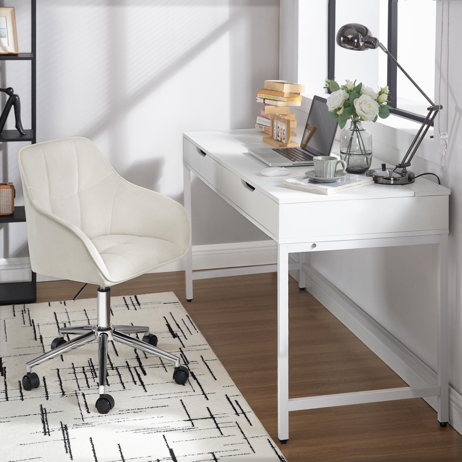 Ein weißer Schreibtisch mit Laptop und Lampe, ein passender weißer Stuhl und ein gemusterter Teppich im hellen Zimmer.